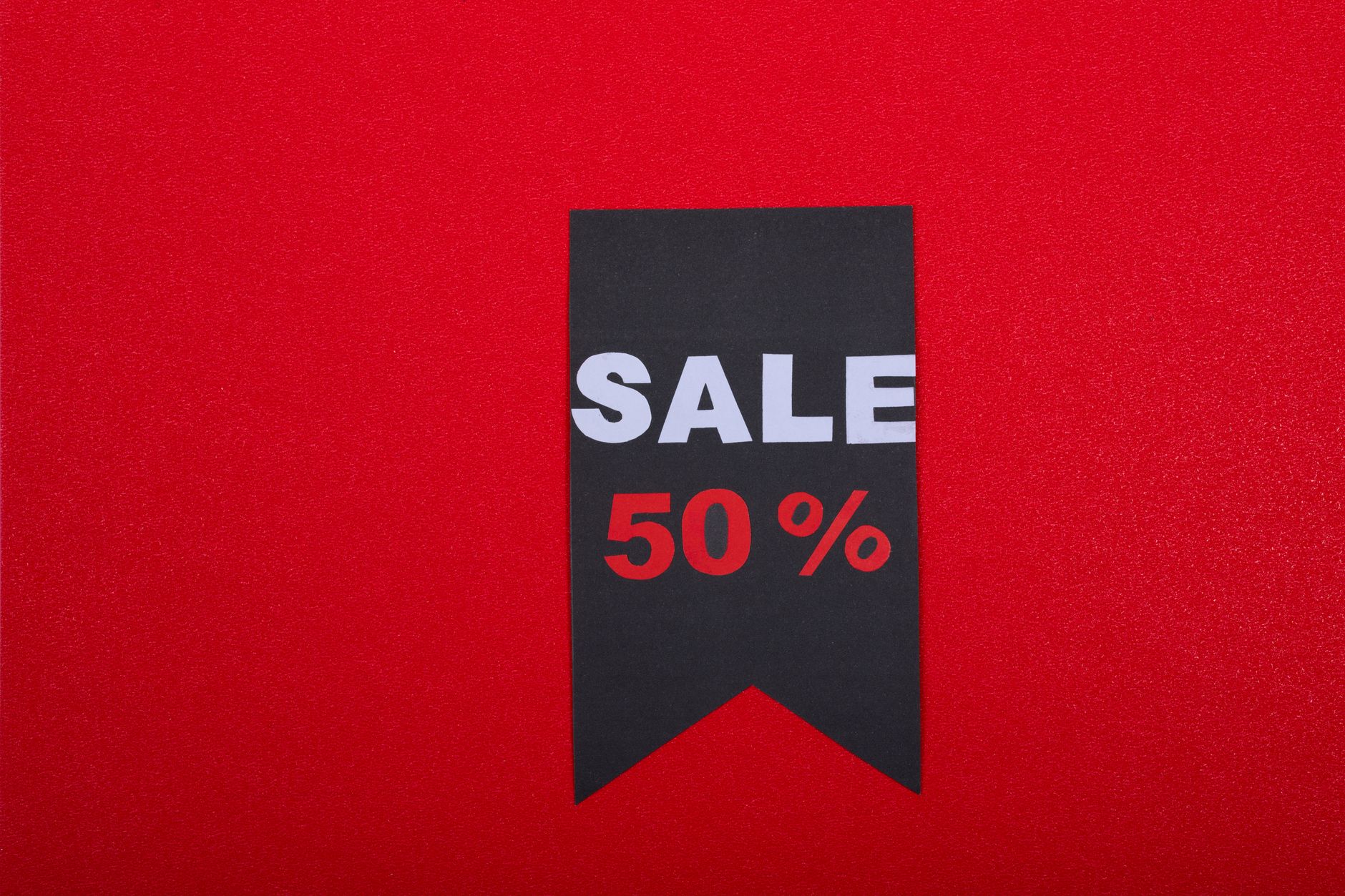 Black sale tag on red background highlighting 50% discount.