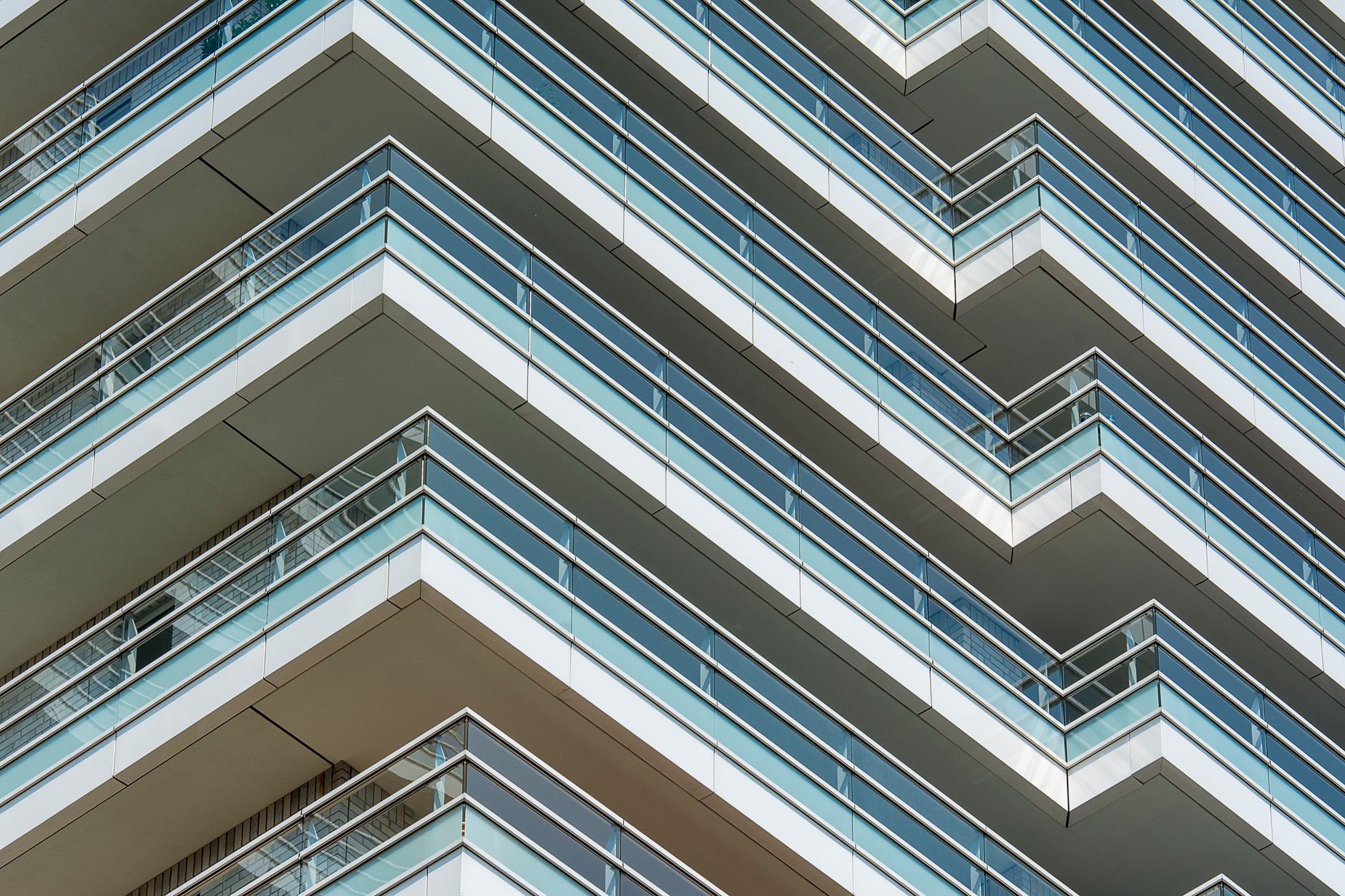 Close-up view of modern apartment building facade with glass balconies in an urban setting.
