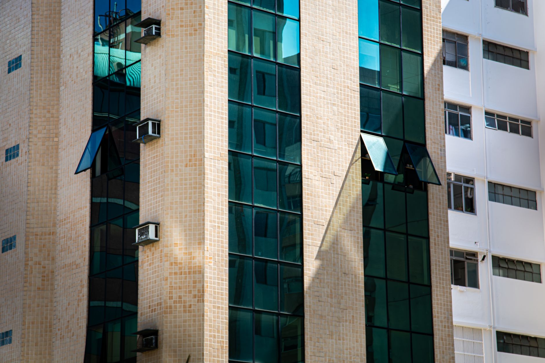 A detailed view of a modern office building facade with green glass and tile exterior in São Paulo, Brazil.