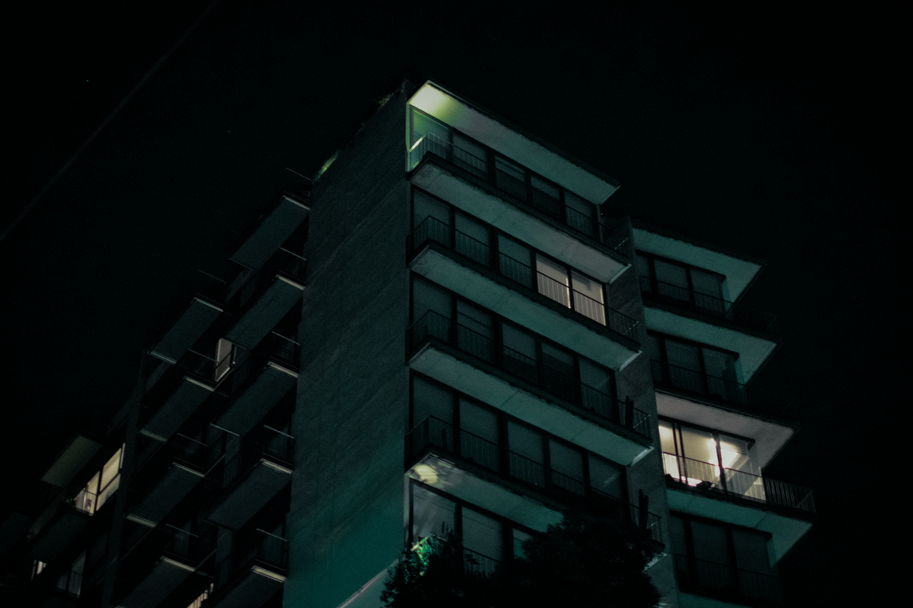 Dramatic view of a modern apartment building illuminated against the night sky.