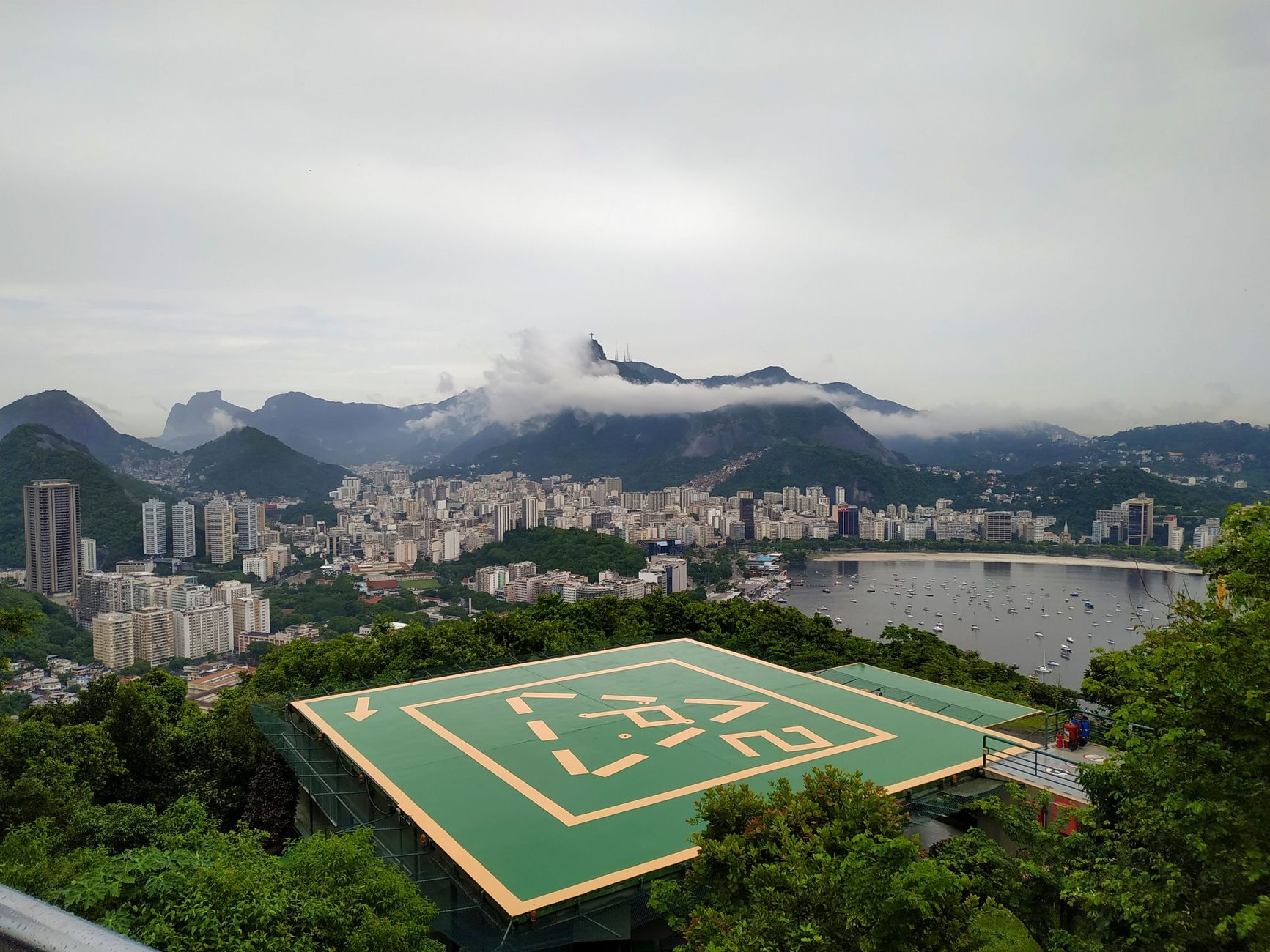 Stunning aerial view of Rio de Janeiro's cityscape with lush greenery and a visible helipad in the foreground.