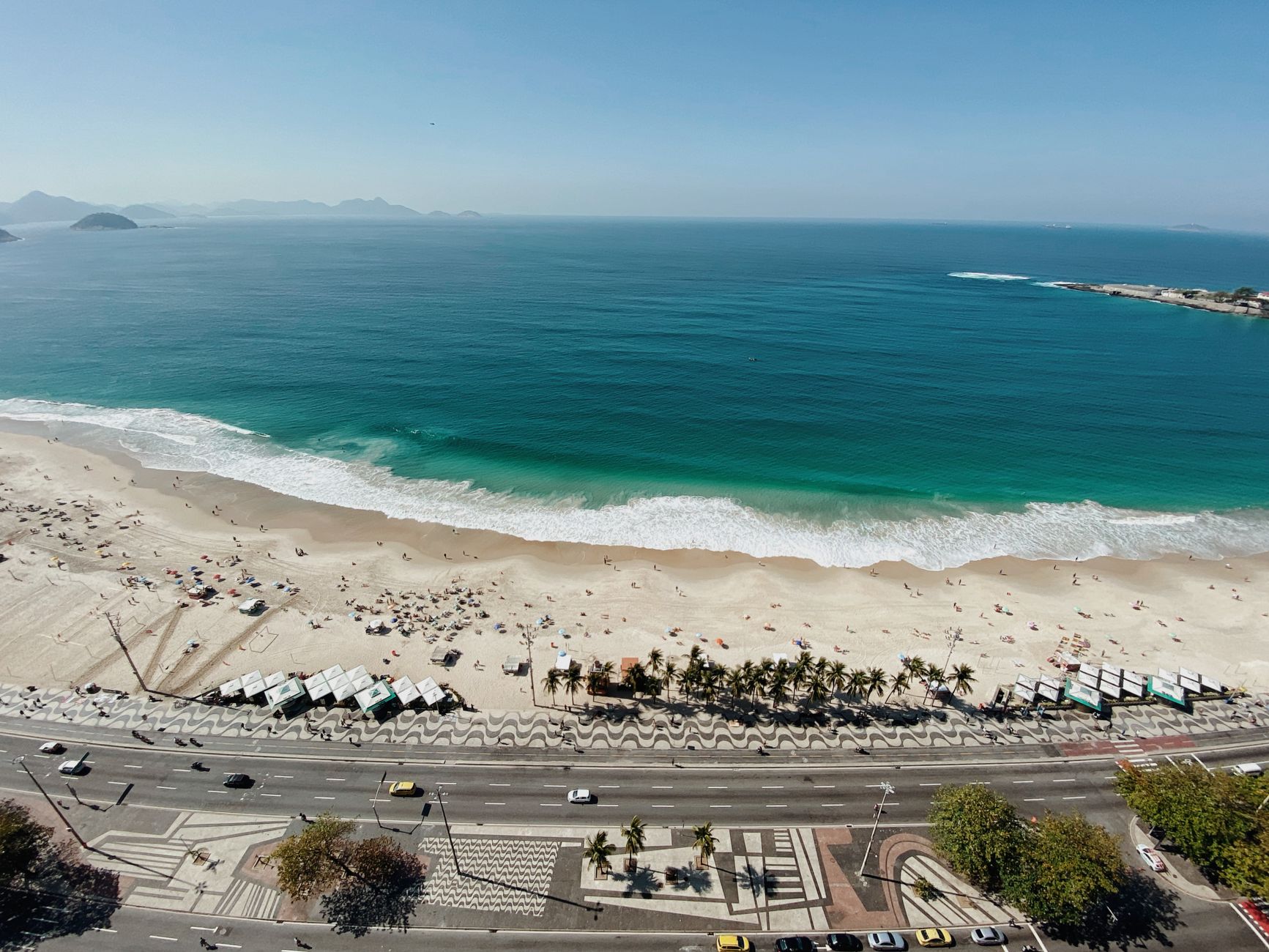 Stunning aerial view of iconic Copacabana Beach with teal ocean and waving patterns in Rio de Janeiro.