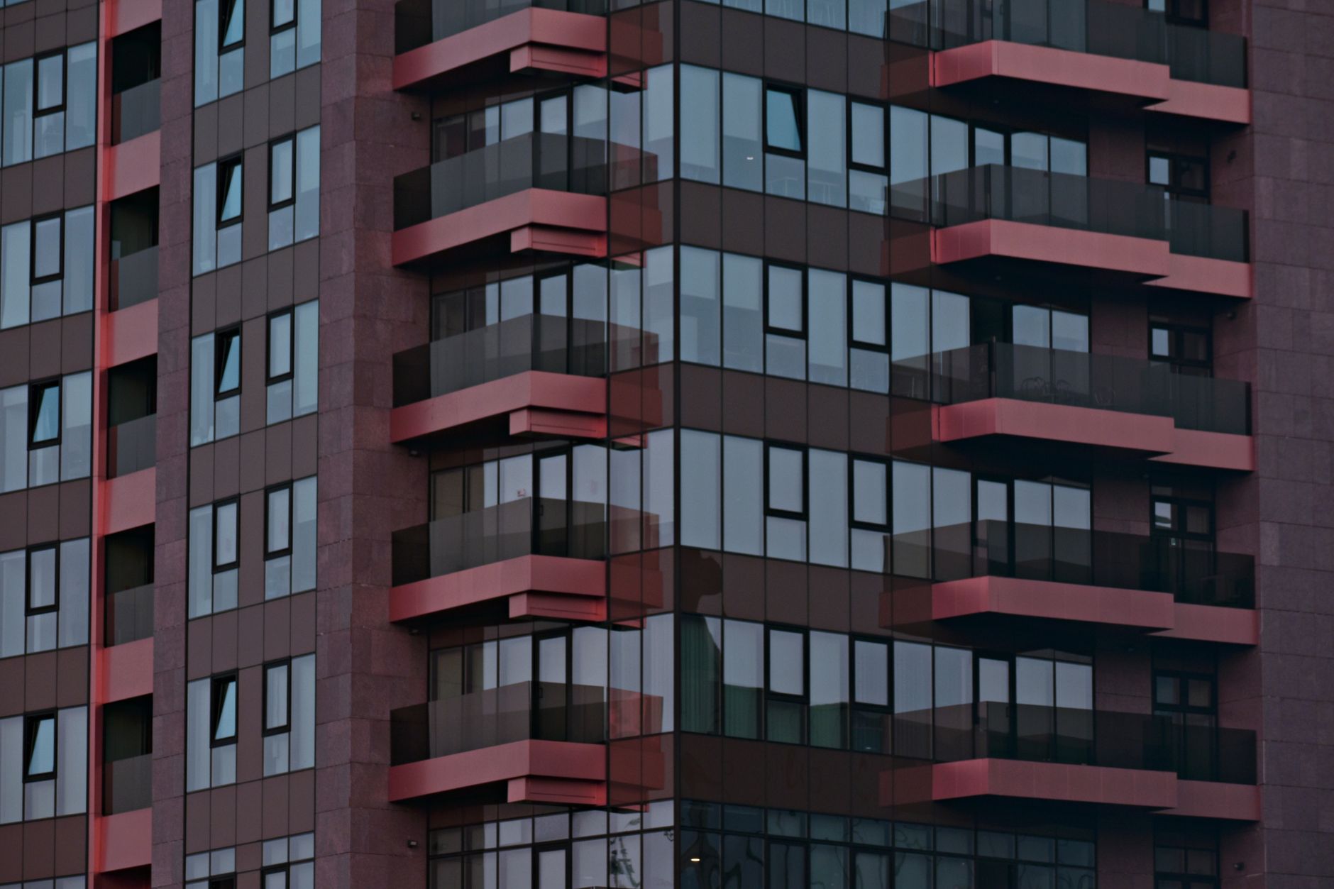 Close-up view of a contemporary building facade with glass windows and balconies in Iași, Romania.