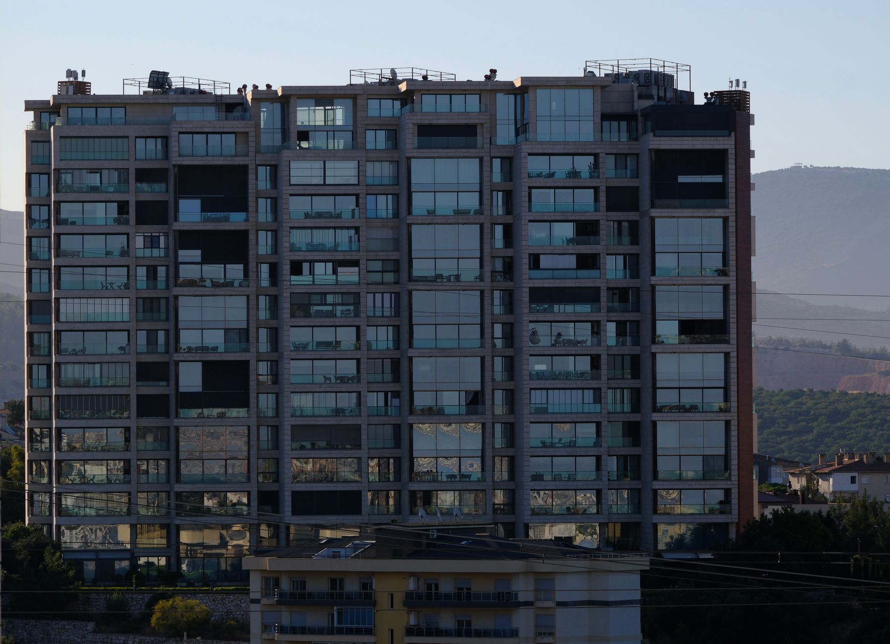 High-rise apartment building in İzmir, Türkiye, with mountains in the background.