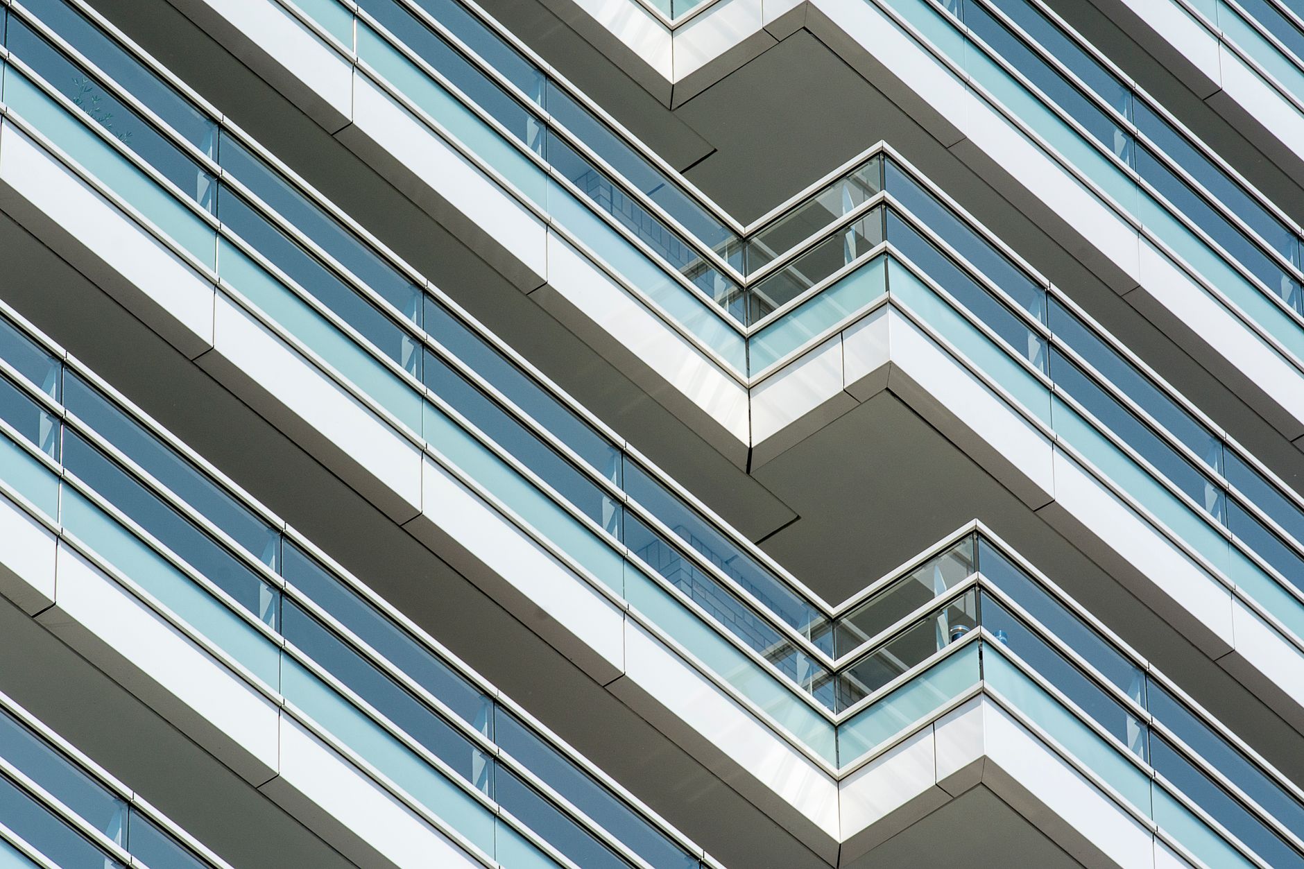 A striking view of modern architectural balconies with glass railings showcasing geometric patterns.