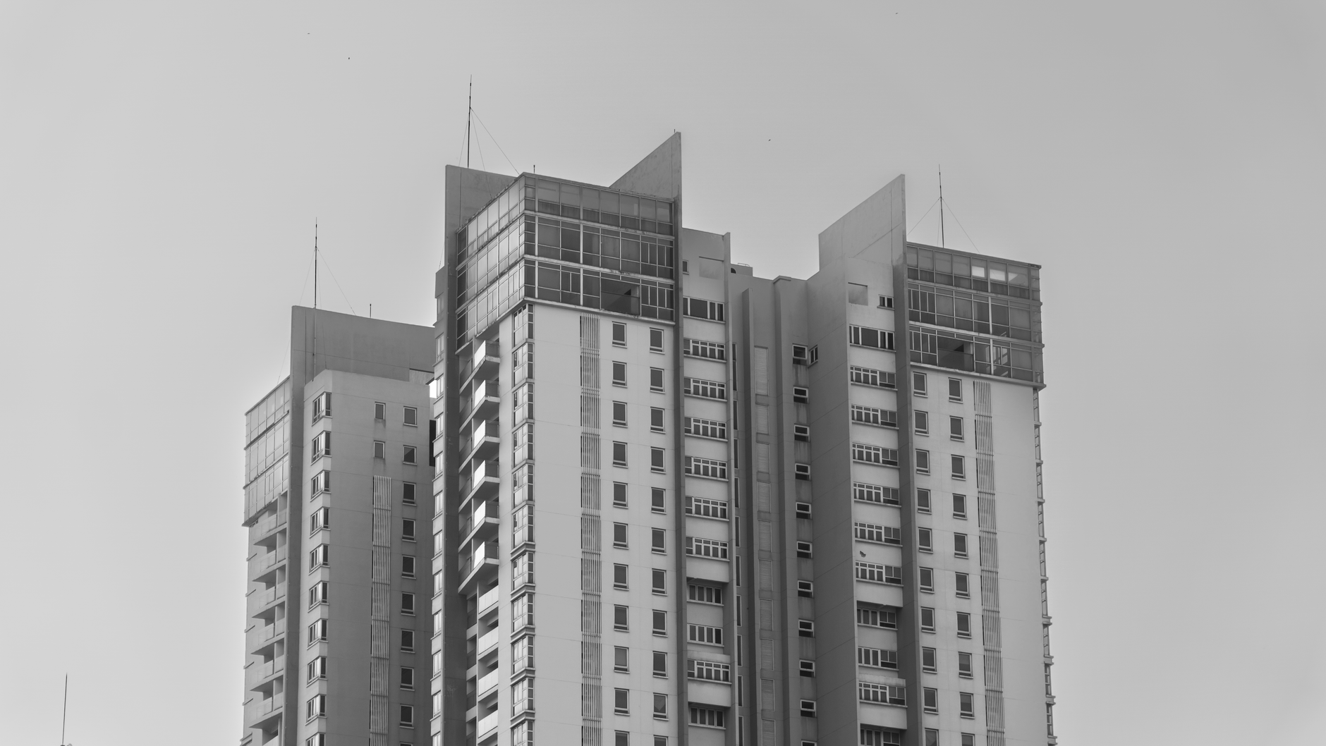 Monochrome image of a modern high-rise building against a clear sky.