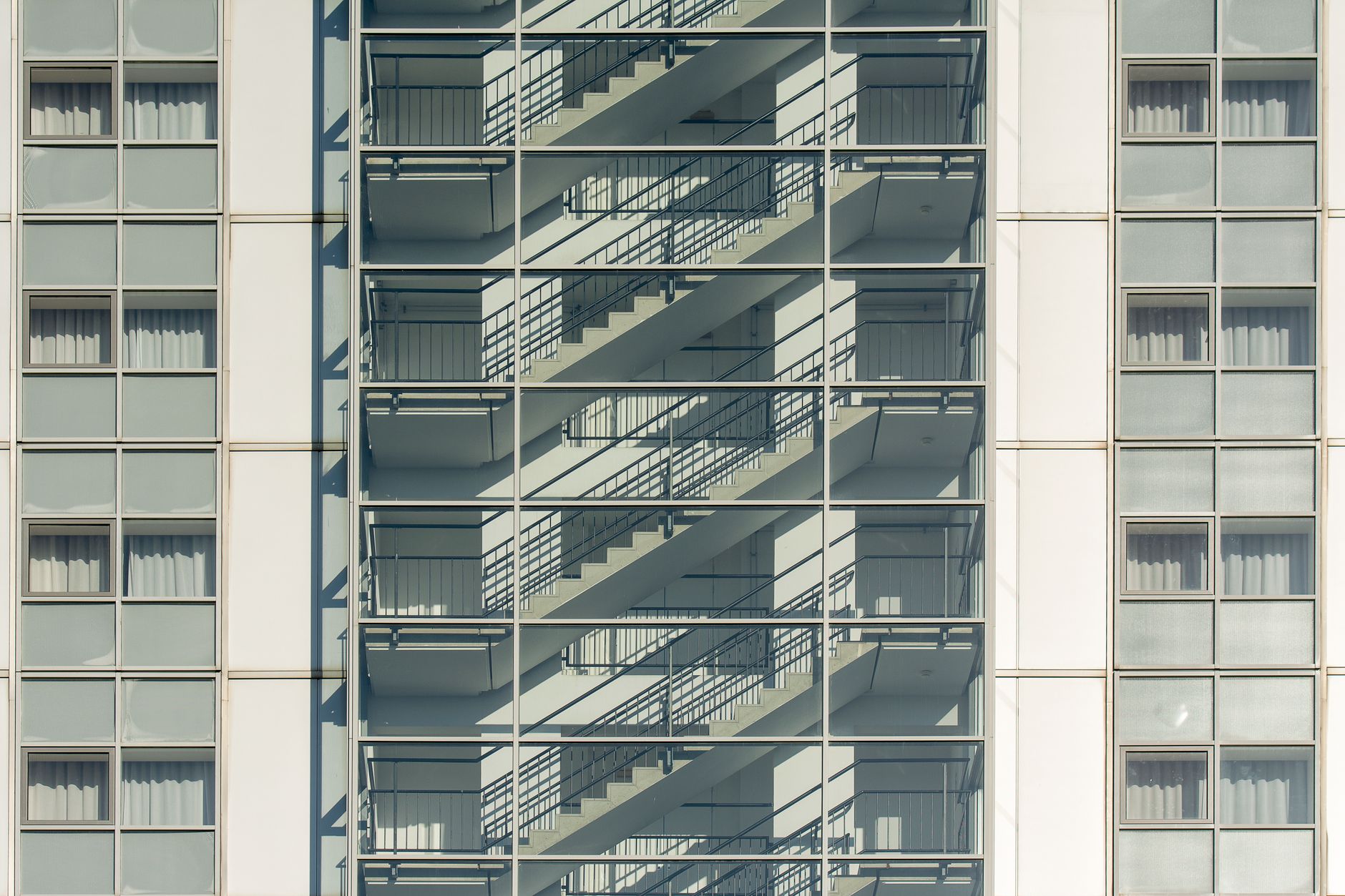 Close-up of a modern apartment building facade with an external staircase casting shadows.