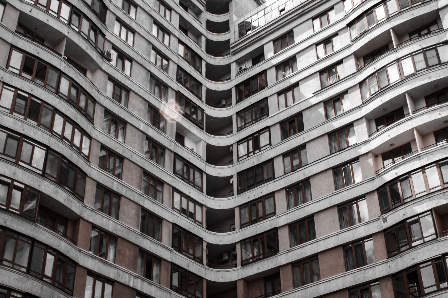 Low angle view of a modern apartment building with glass windows and curved design.