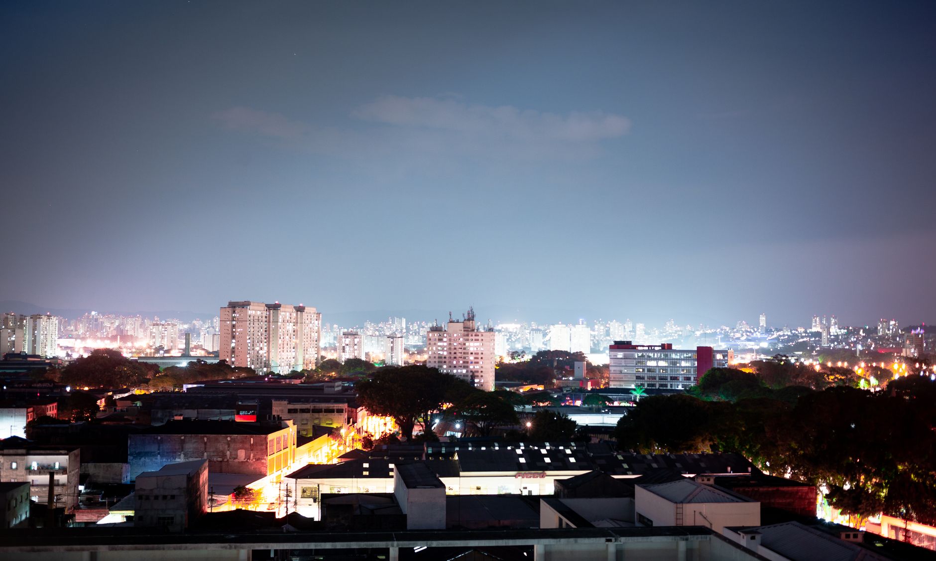 A vibrant cityscape captured at night featuring illuminated buildings and a clear night sky.