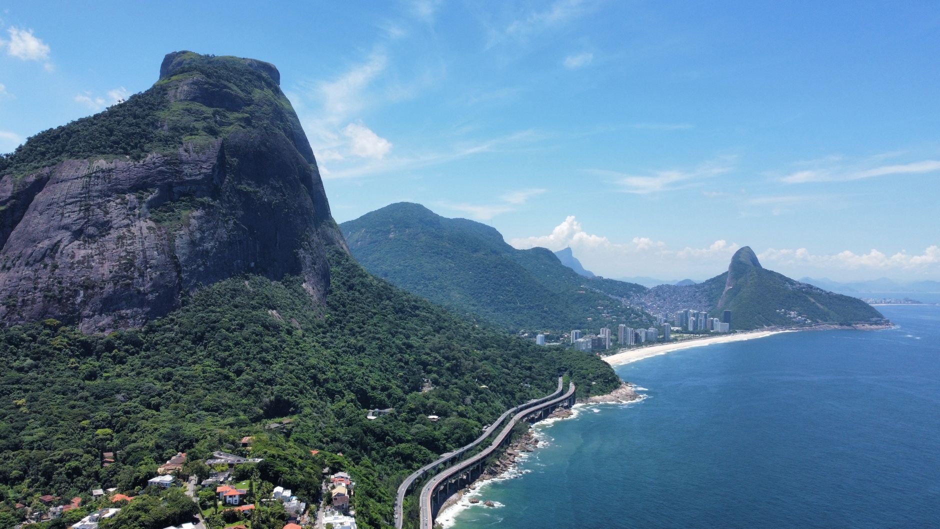 Stunning aerial view of Rio's coastline featuring lush green hills and the Atlantic Ocean.