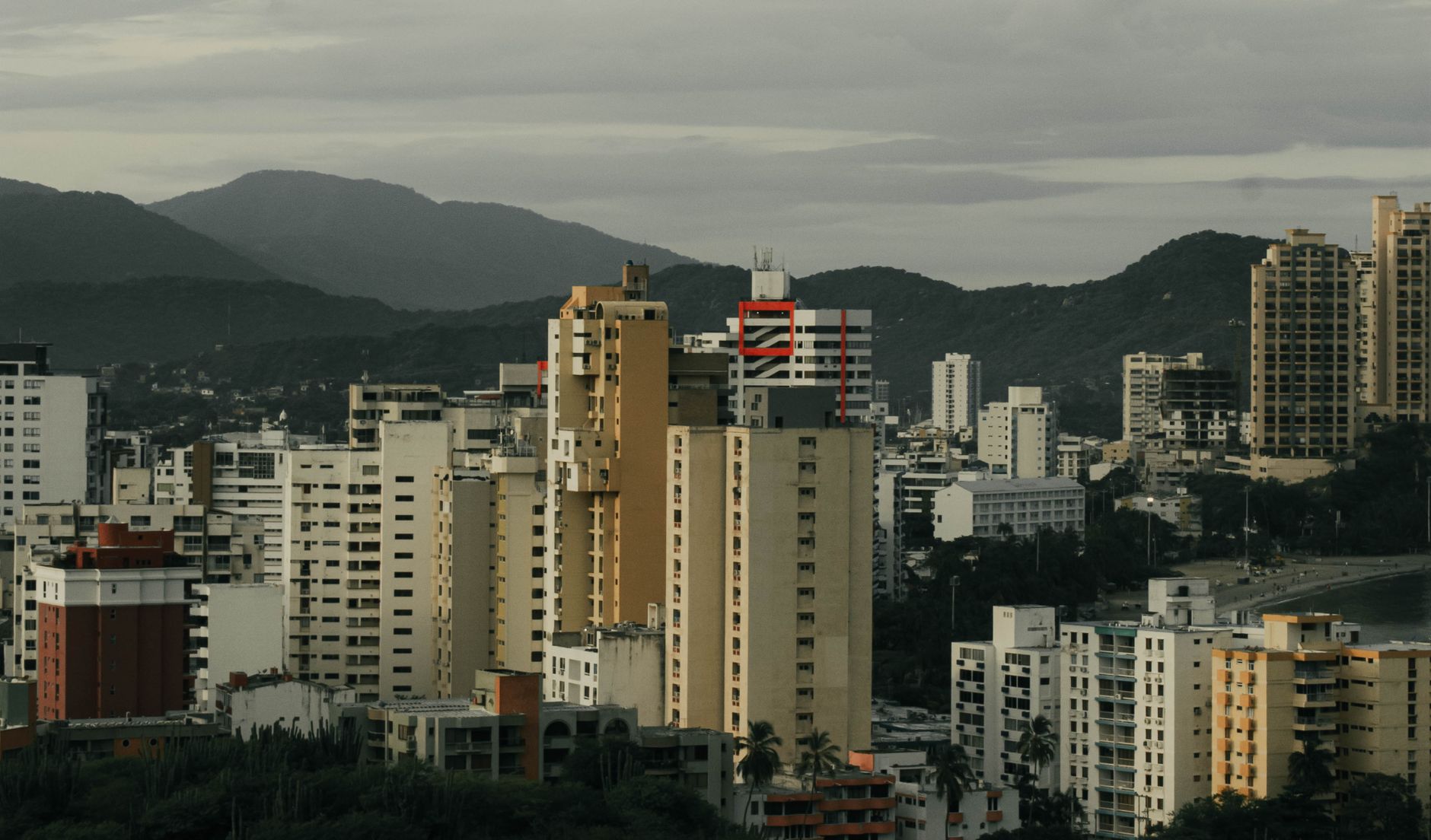 Elevated view of Santa Marta's urban skyline with distant mountains under a cloudy sky.