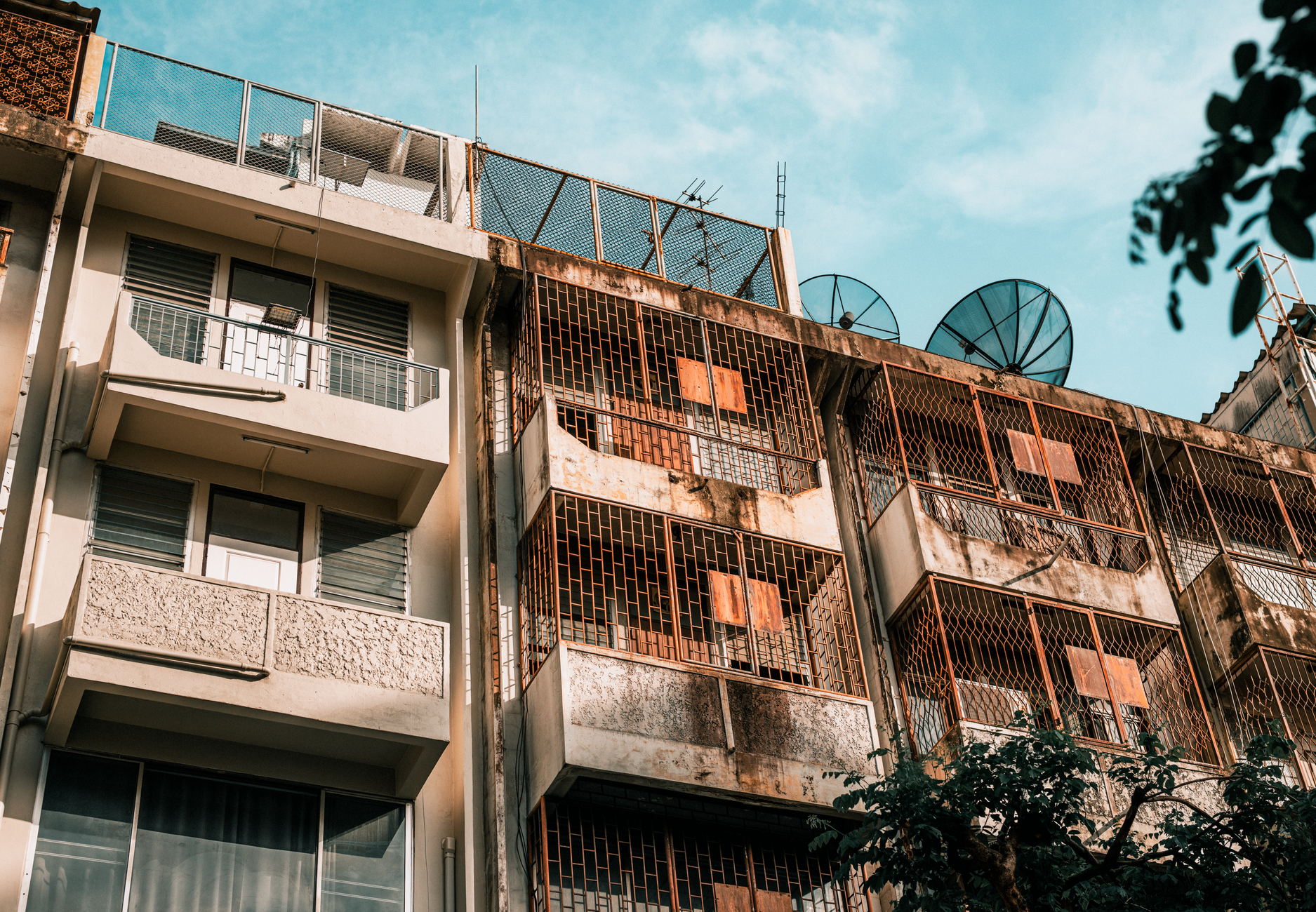 Old apartment buildings with satellite dishes under a clear sky in Bangkok, Thailand.