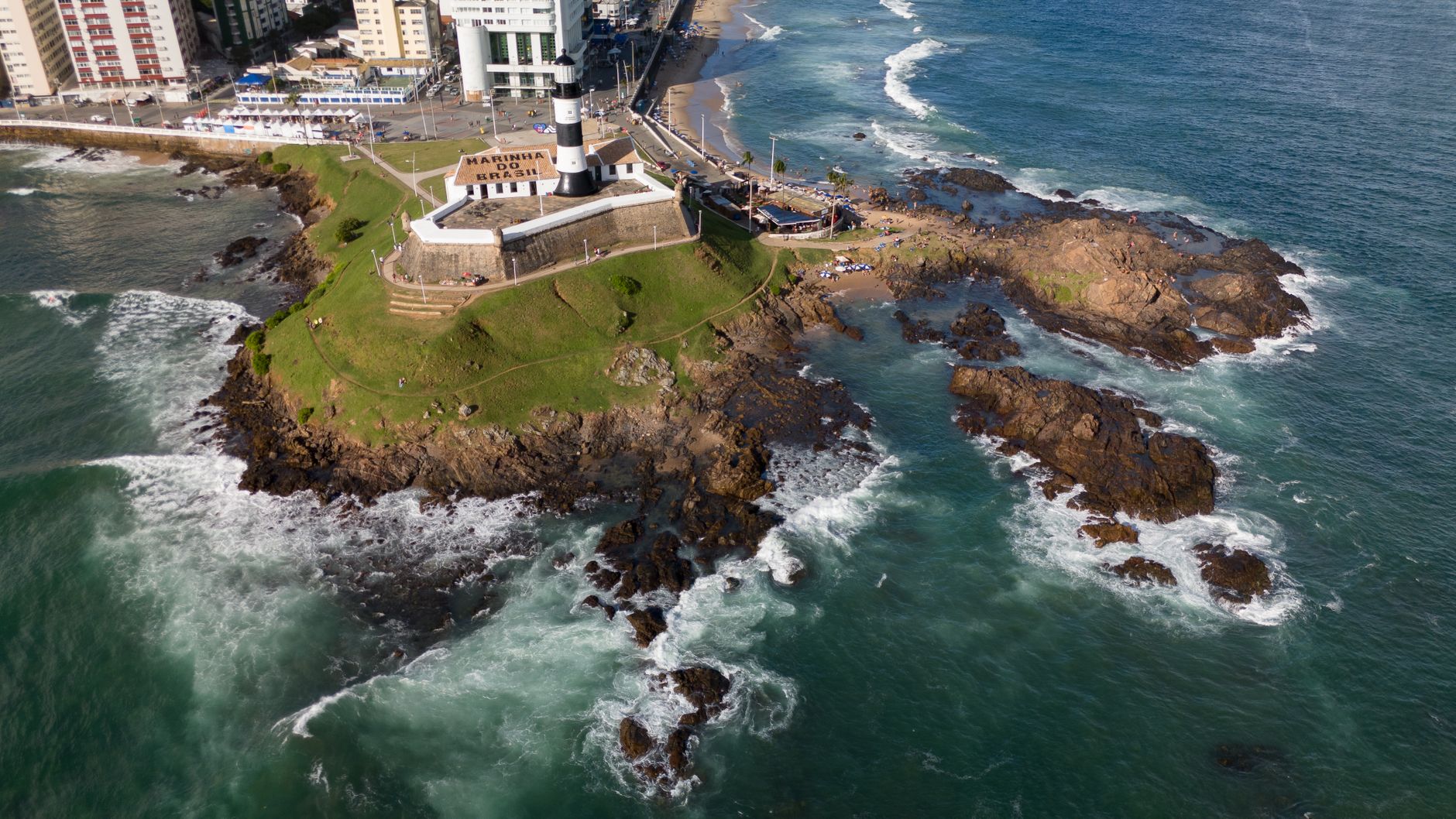 A stunning aerial view of the iconic Barra Lighthouse and surrounding coast in Salvador, Brazil.