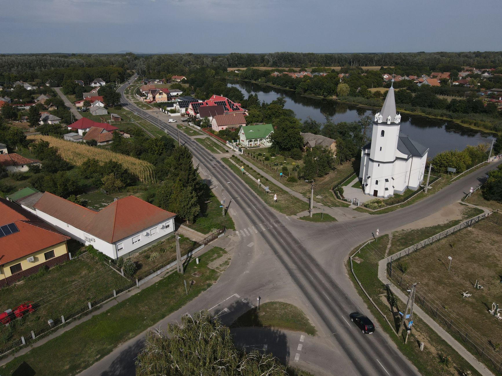 Aerial shot of the picturesque church and river in Tunyogmatolcs, Hungary, showcasing rural charm.