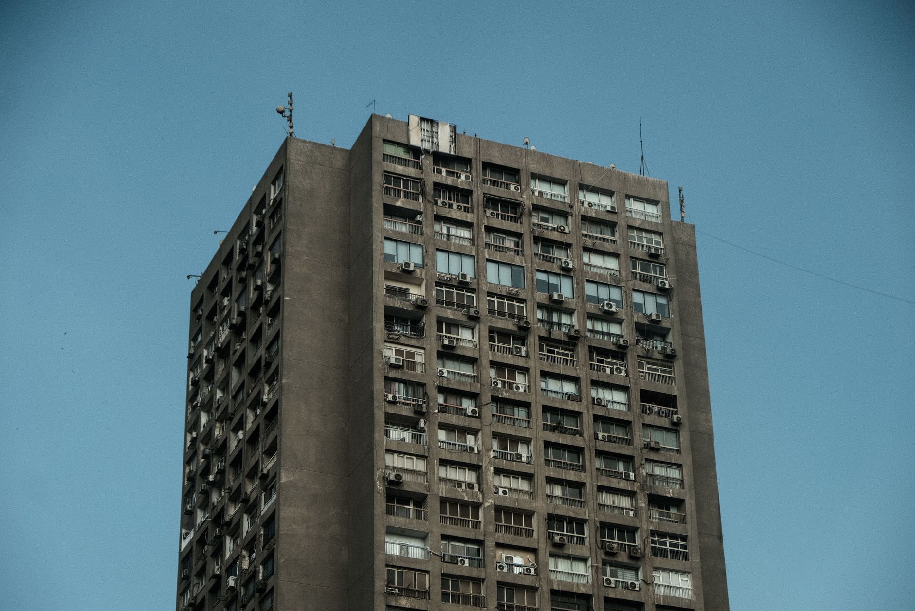 A vintage brutalist tower with weathered concrete facade against a clear blue sky in Cairo, Egypt.