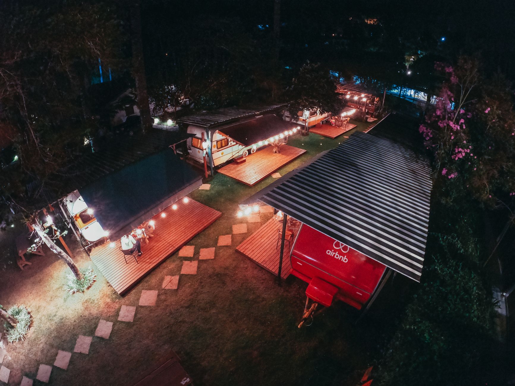 Aerial view of trailers for tourists at camping area decorated with sparkling garlands at night