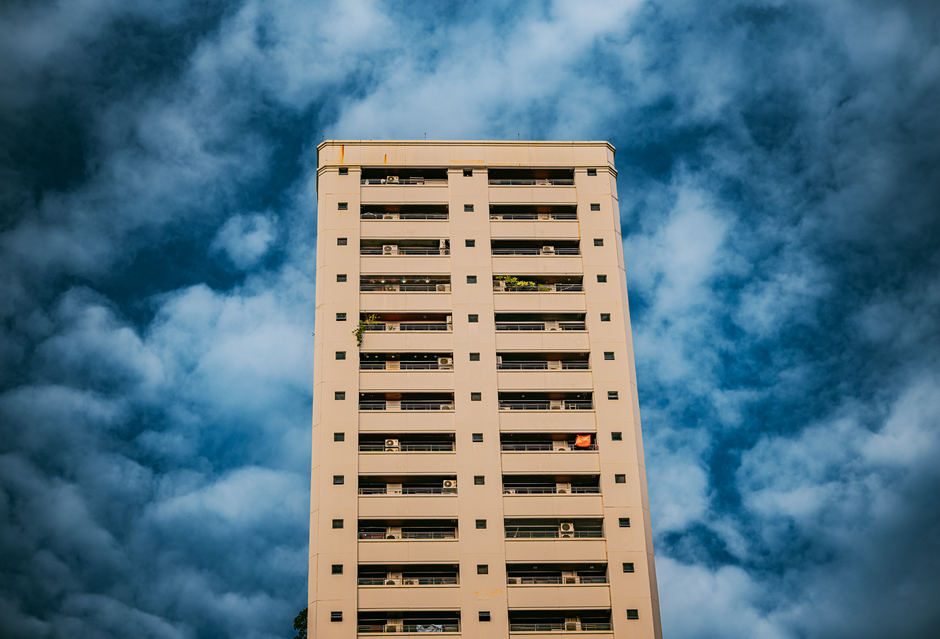 Modern high-rise building set against a dramatic cloudy sky in Bangkok, Thailand.