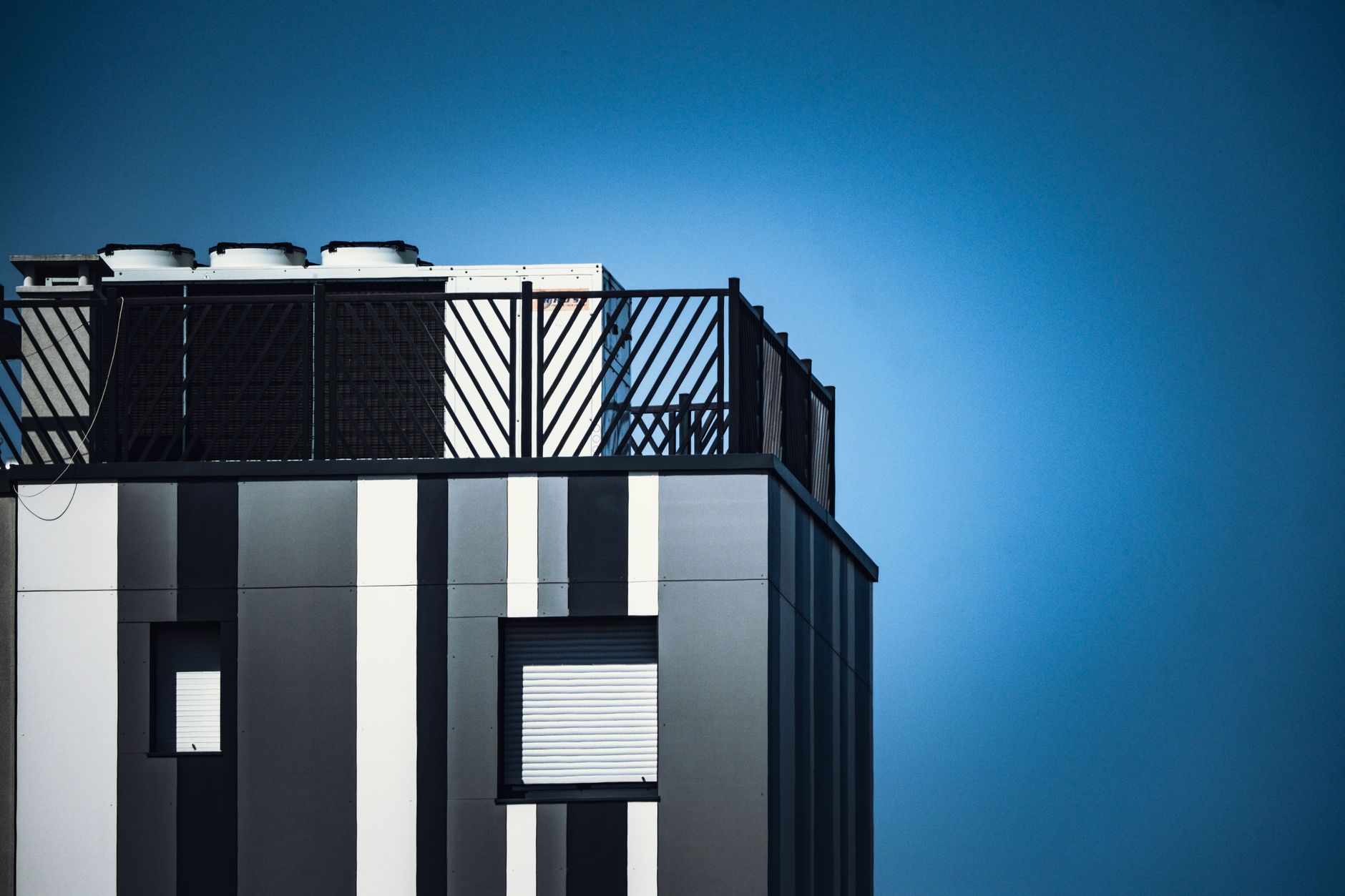 Contemporary urban building facade with striped design and blue sky backdrop.