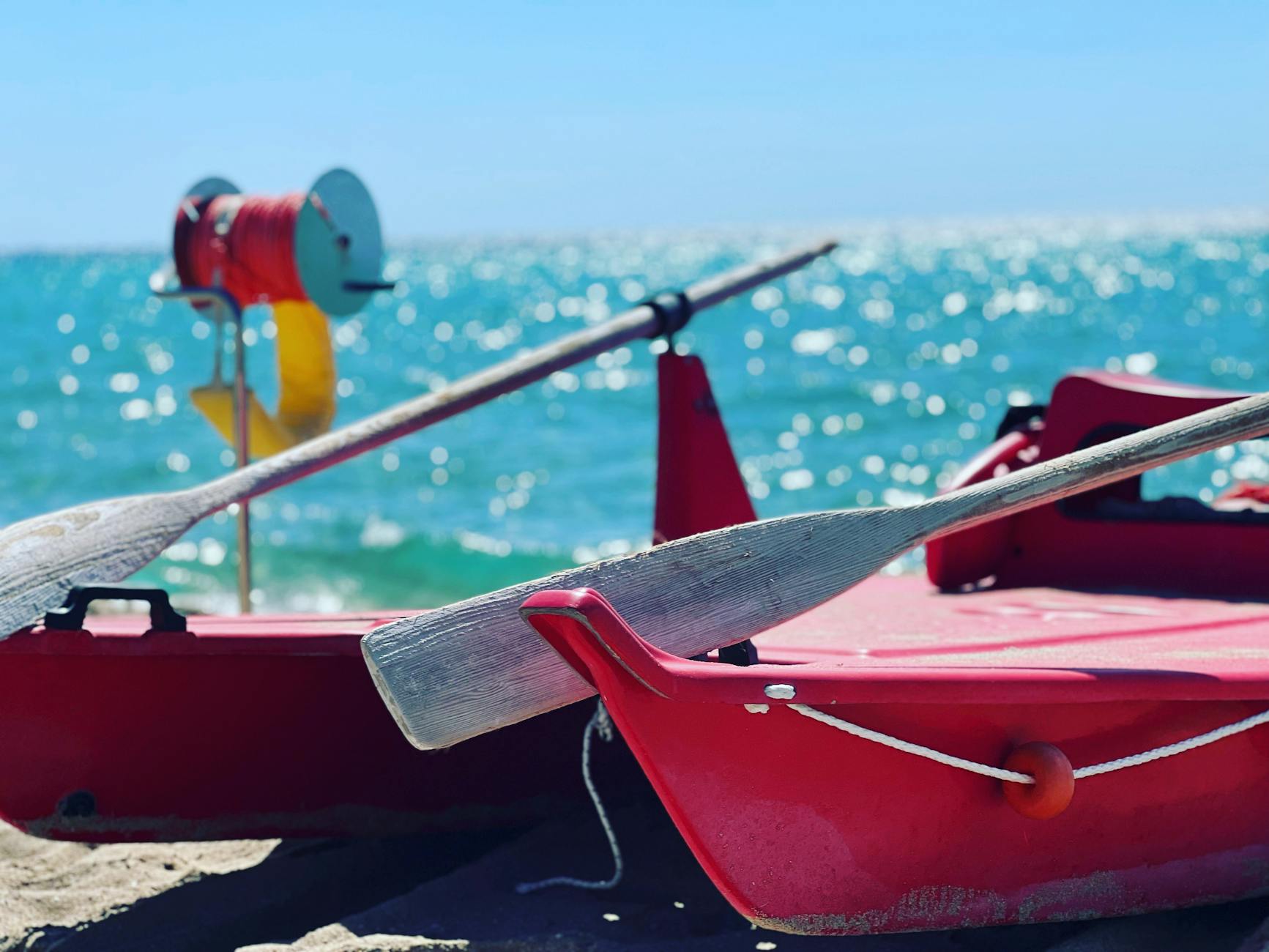 Vibrant red boat and oars on a sunny day at the shore in Puglia, Italy.