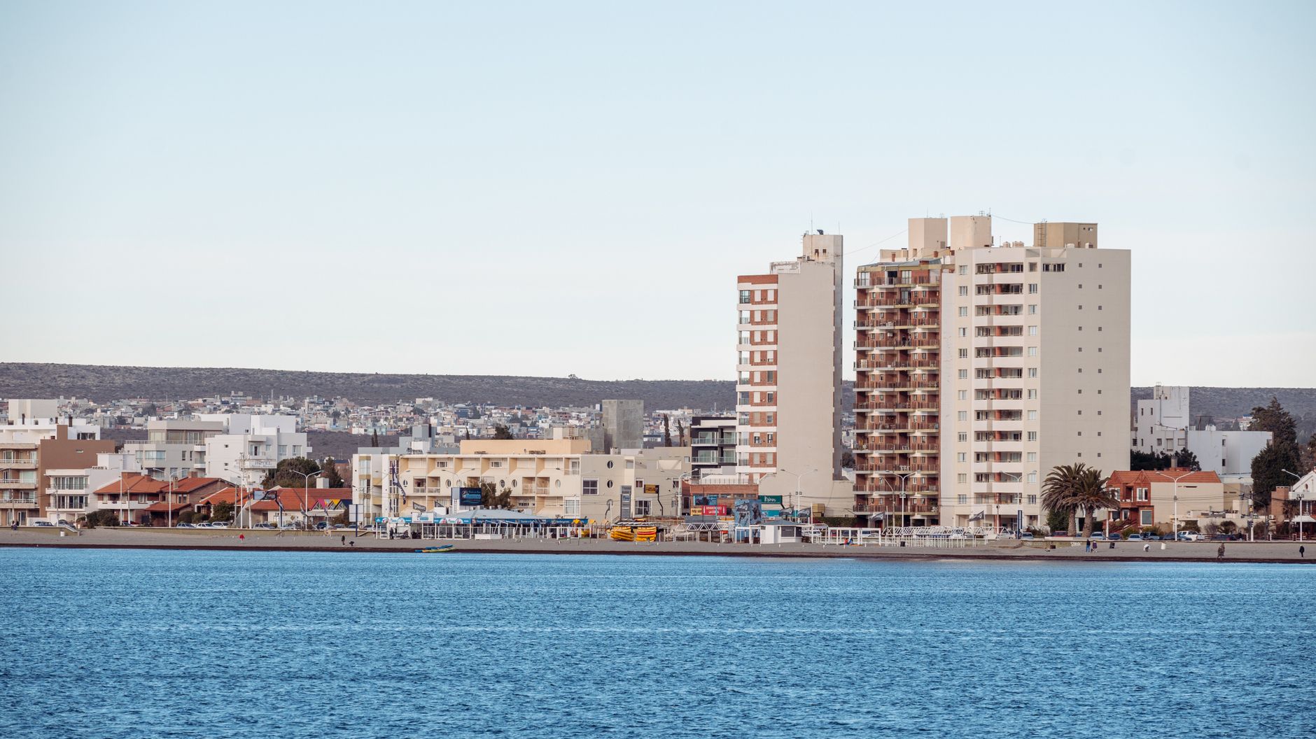 A modern coastal cityscape with tall buildings along a waterfront, showcasing urban development.