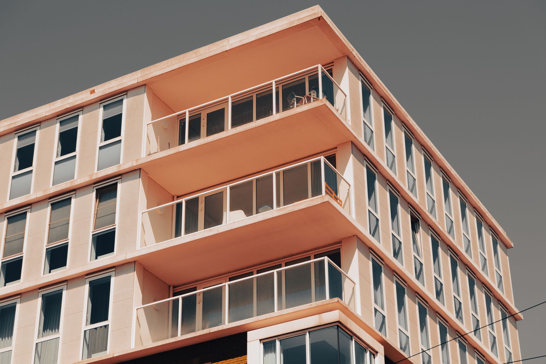 Exterior view of a modern apartment building with balconies and large windows under a clear sky.