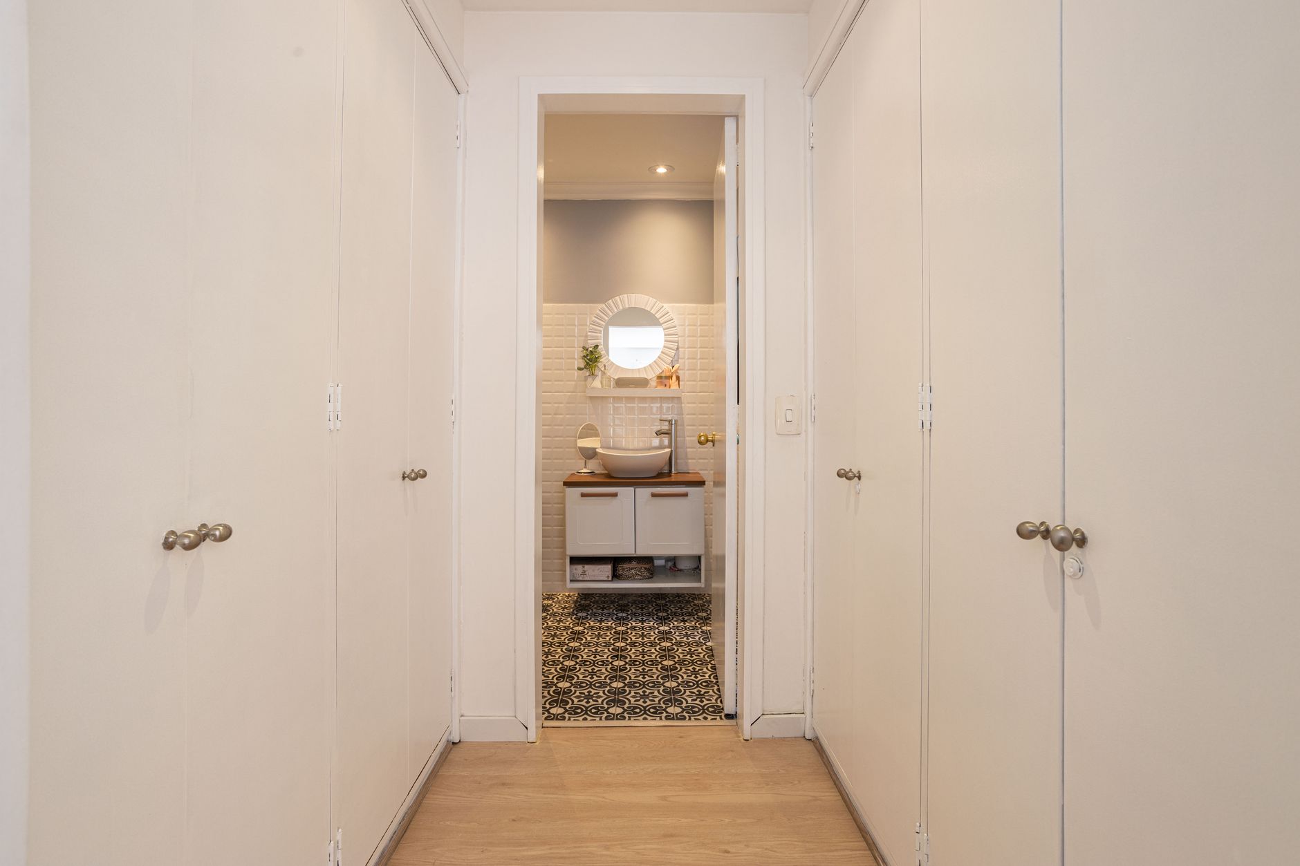 Elegant narrow hallway with white closets leading to a stylish bathroom featuring modern decor in Bogotá.