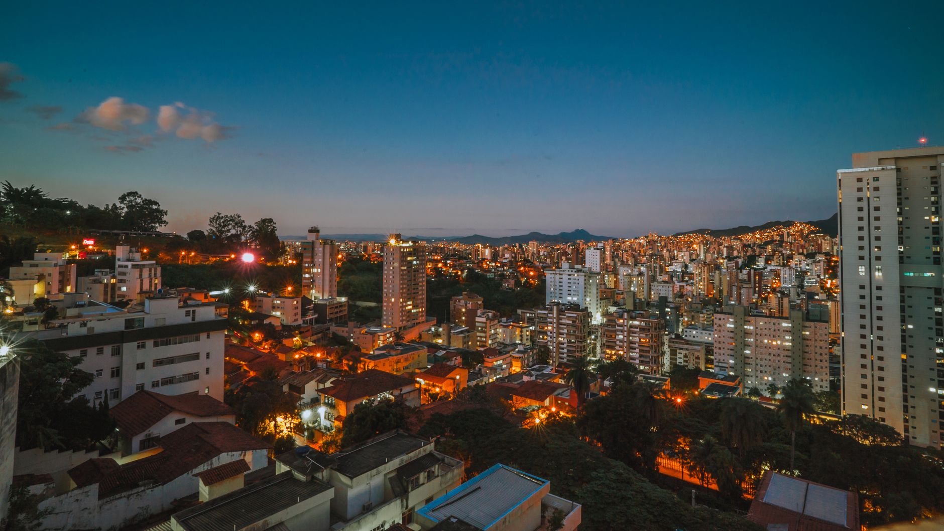 A vibrant urban skyline of Belo Horizonte at twilight showcasing illuminated buildings and scenic views.