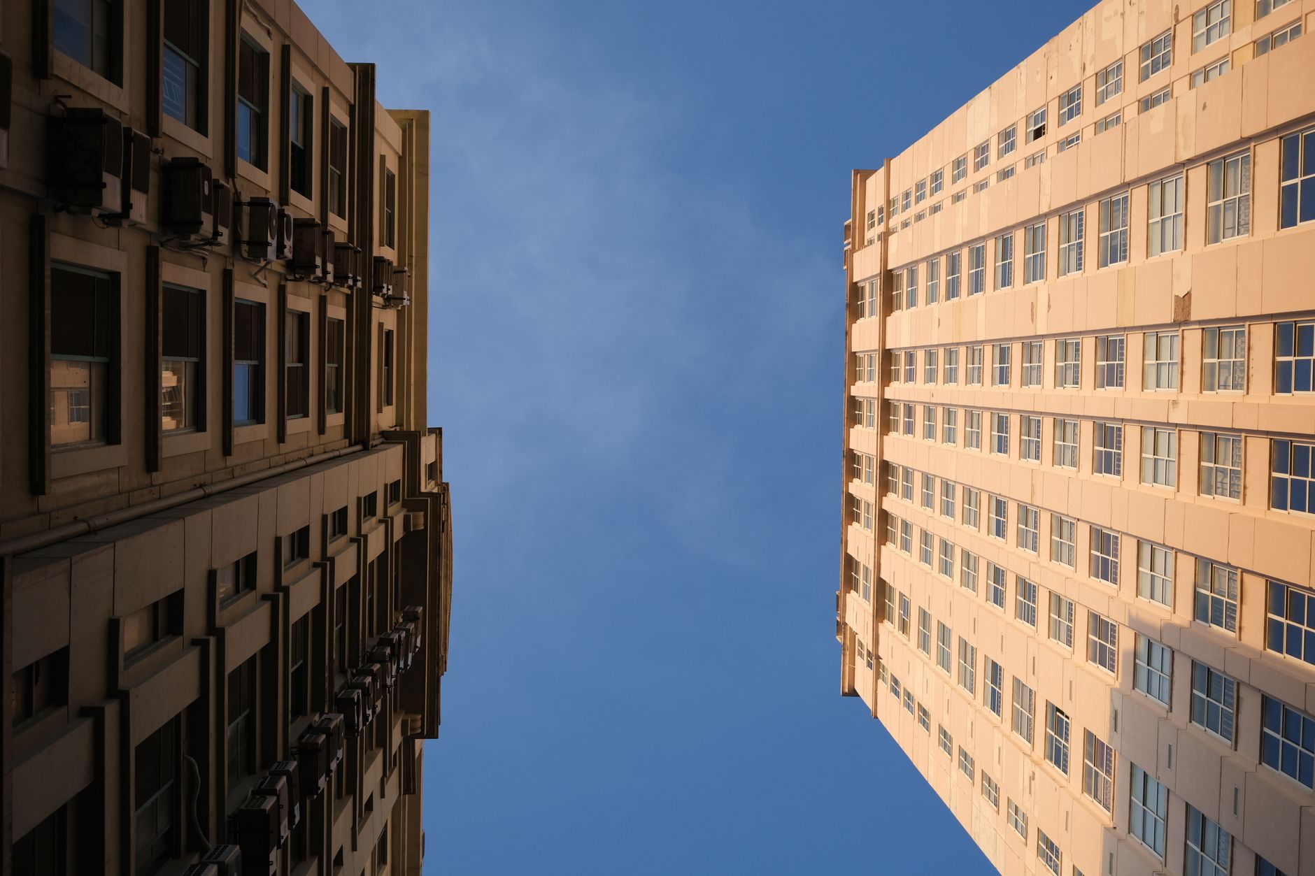 Dynamic low-angle view capturing high-rise buildings against a clear blue sky.