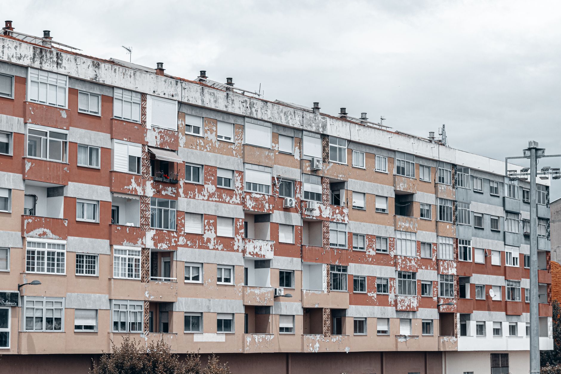 A large urban apartment block featuring a weathered facade with peeling paint and balconies.