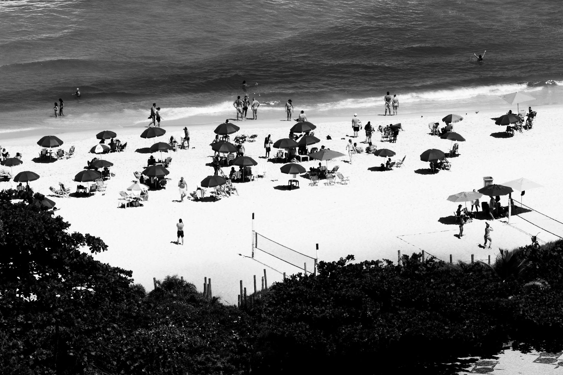 A lively black and white aerial scene of people enjoying a sunny day at the beach in Rio de Janeiro, Brazil.