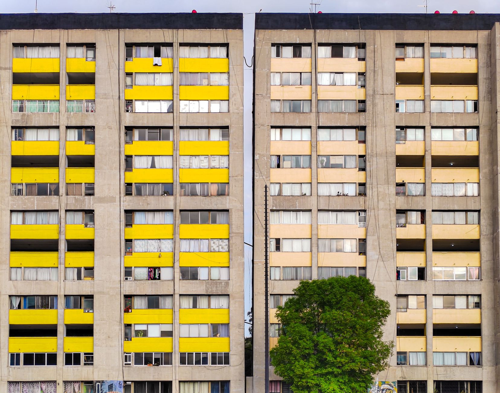 Colorful facades of apartment buildings in Mexico City with vibrant yellow balconies and urban architecture.