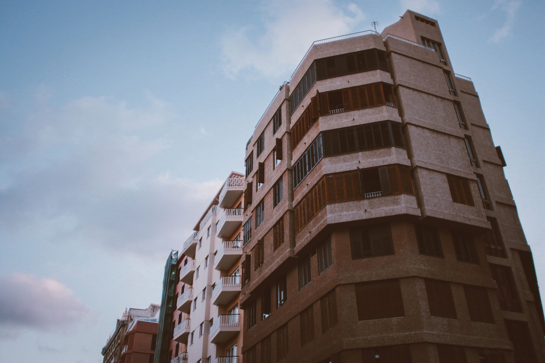 Low-angle shot of a modern building with balconies under a partly cloudy sky.