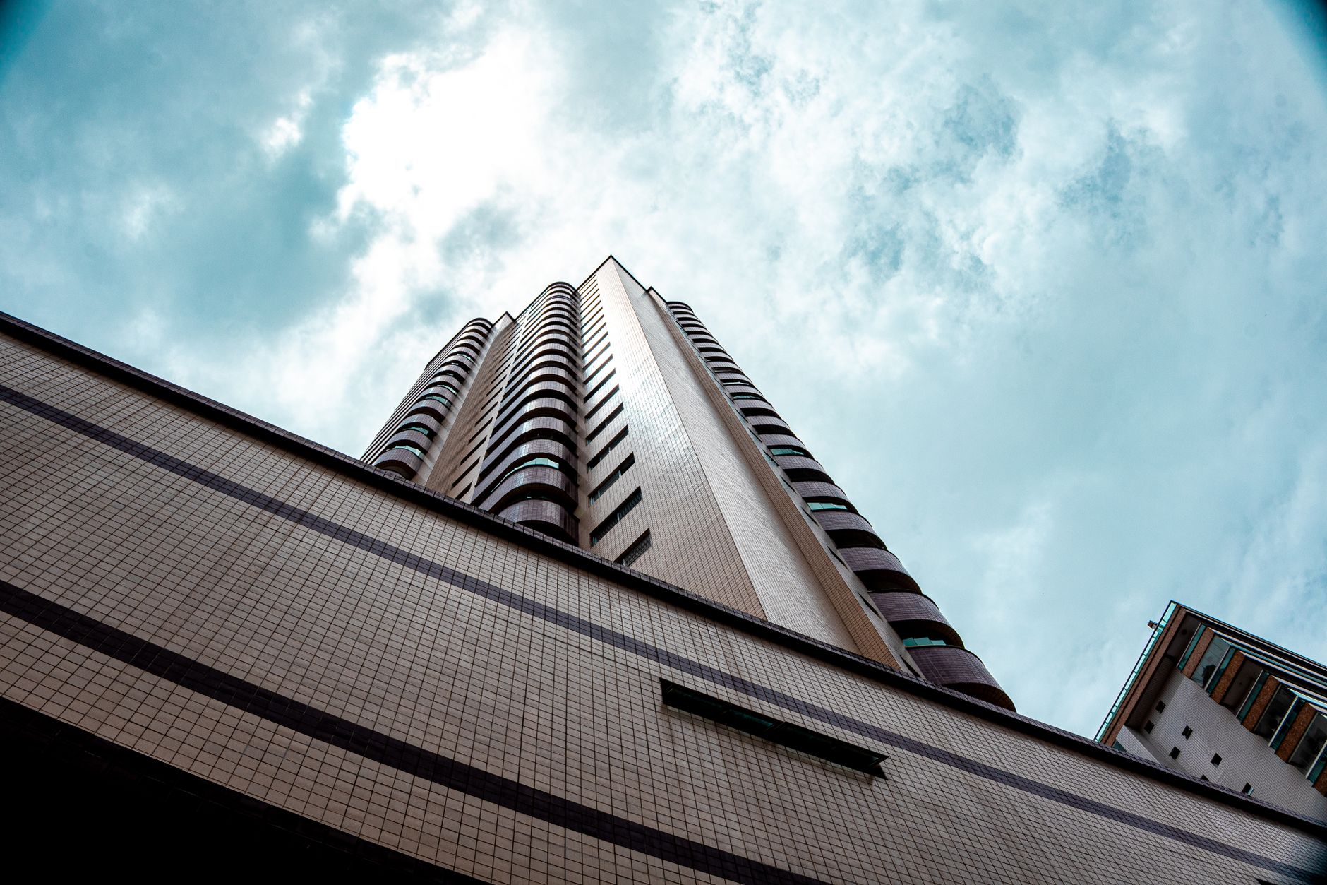 Upward view of a modern skyscraper against a cloudy sky in Praia Grande, São Paulo, Brazil.
