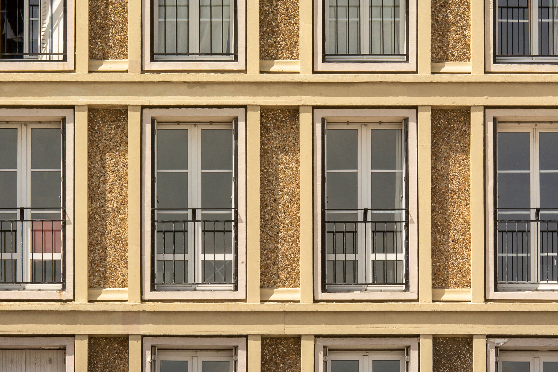 Front view of modern apartment facade with symmetrical windows and balconies.