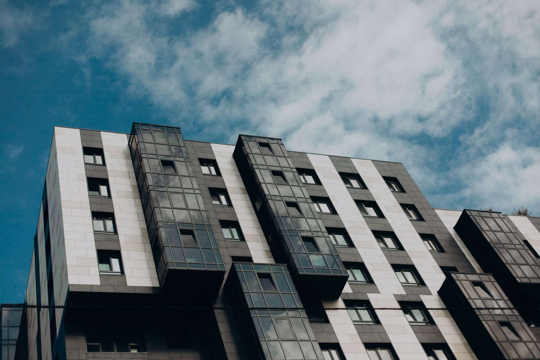 Modern building with glass windows against a vibrant blue sky, showcasing urban architectural design.