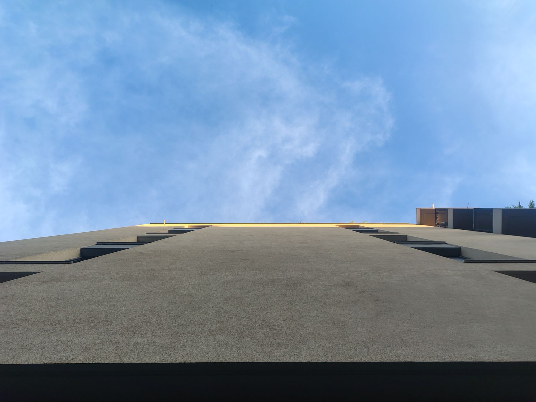 Upward perspective of a modern building under a clear blue sky, emphasizing architecture.