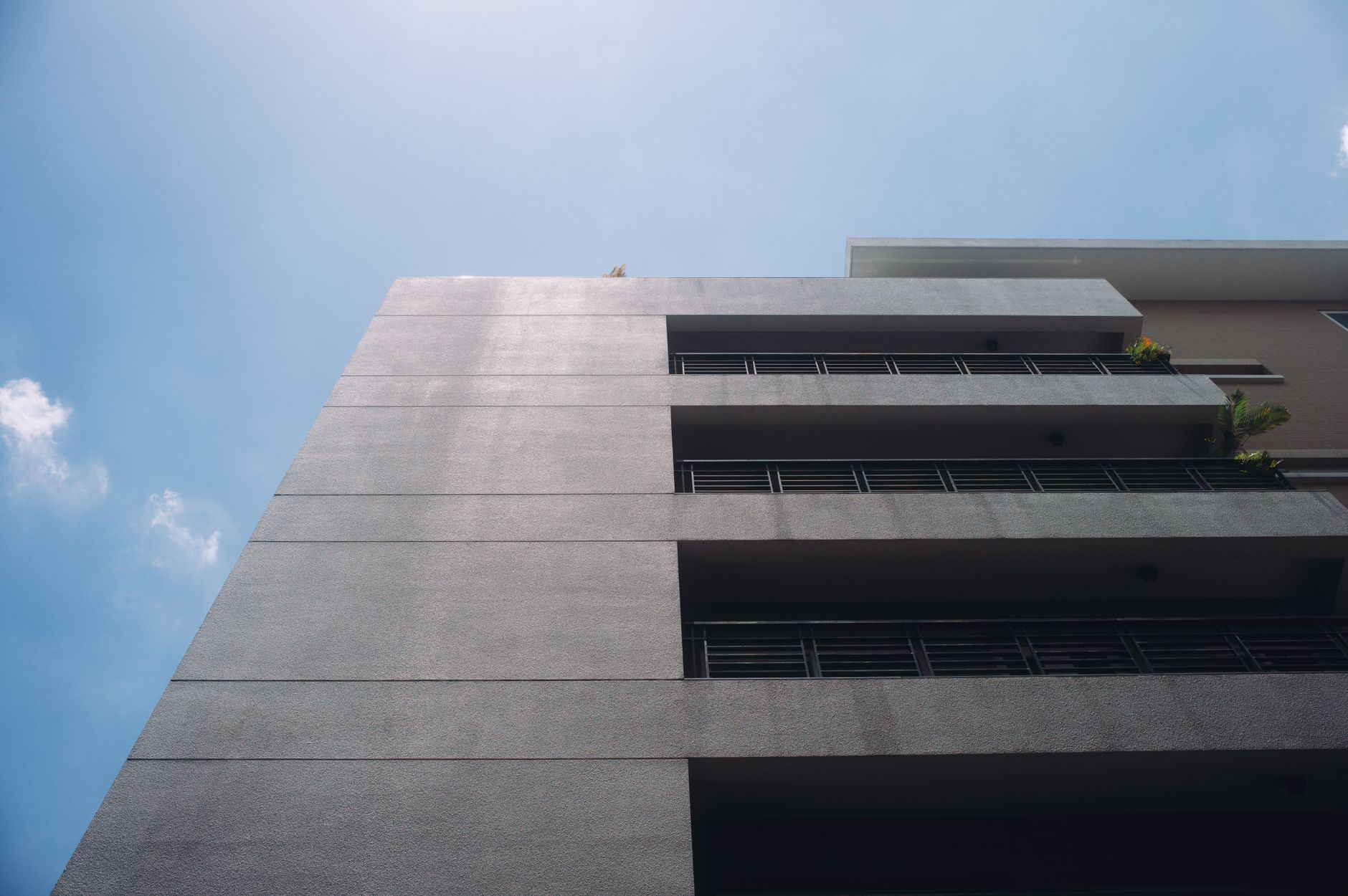 Low-angle view of a modern residential building facade against a clear blue sky.