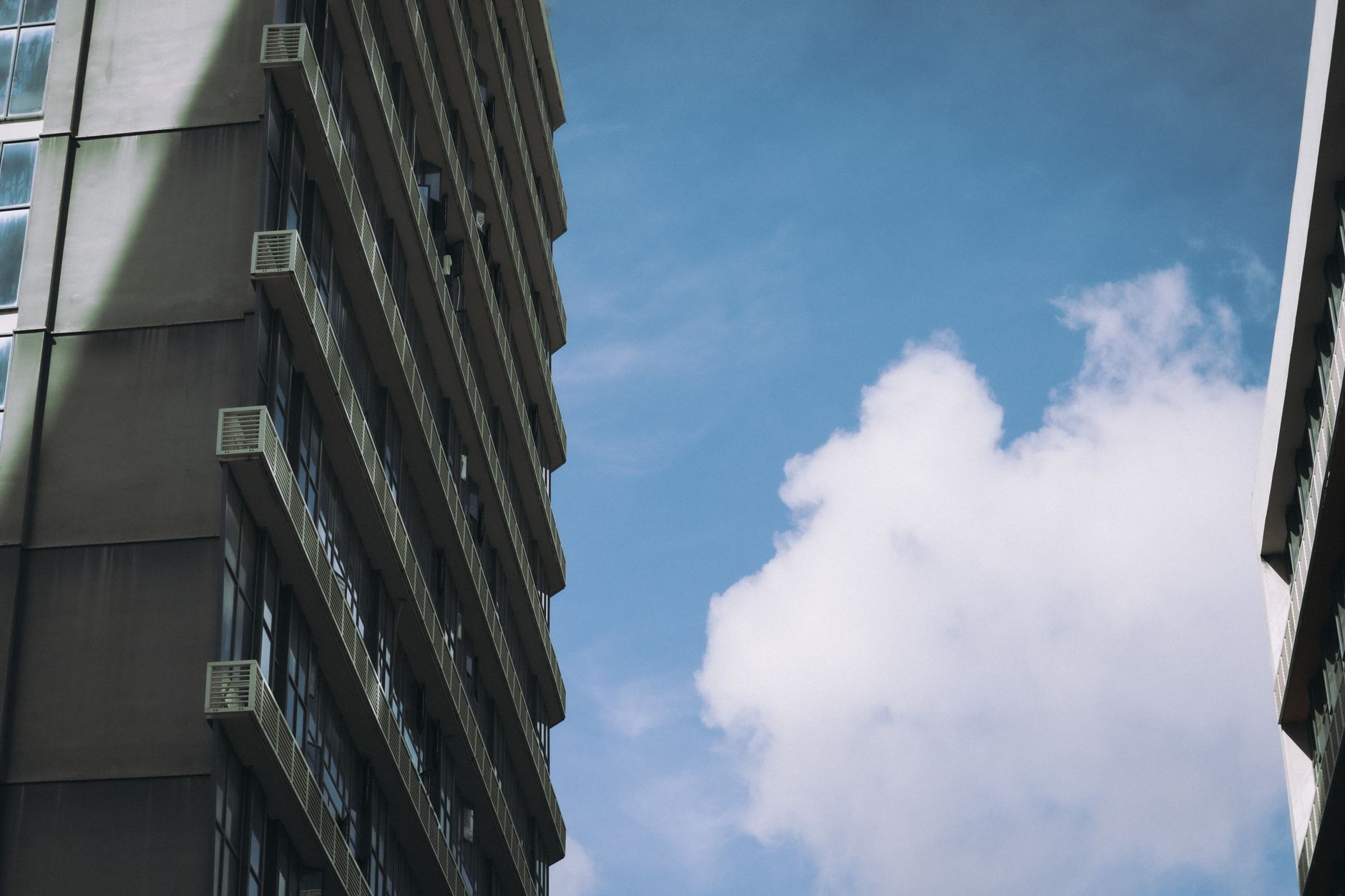 High-rise buildings framing a vibrant blue sky with clouds.