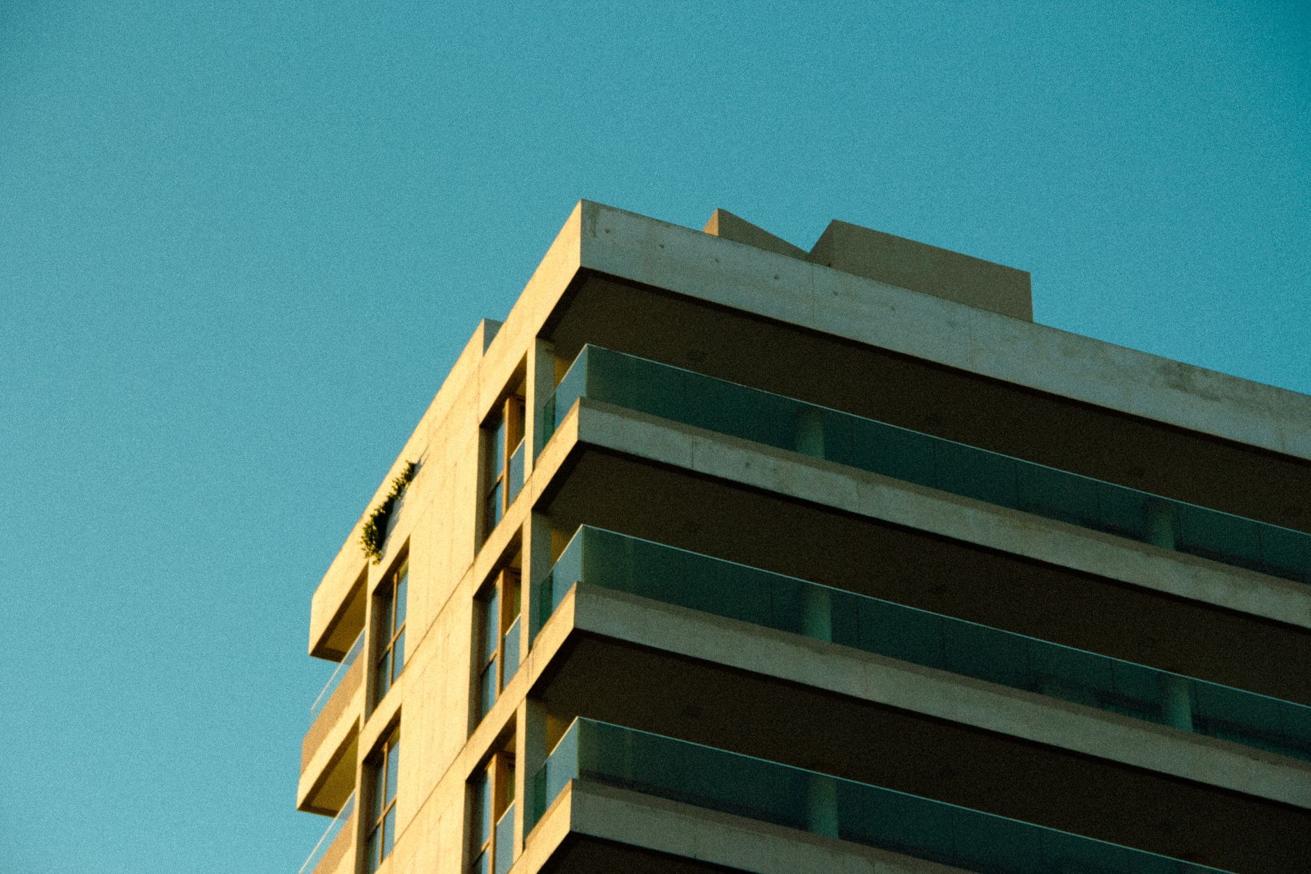 A modern brutalist apartment building basks in sunlight under a clear blue sky.