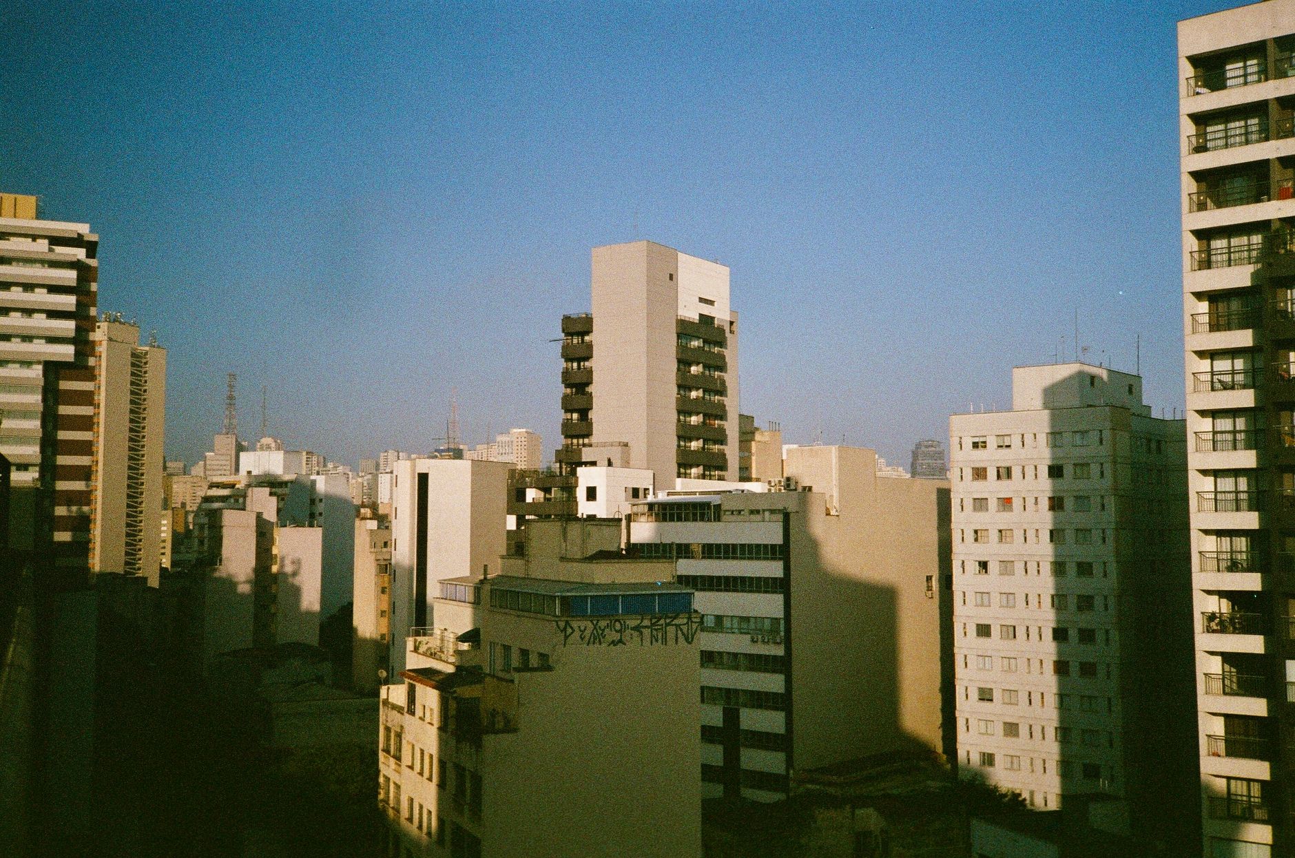 Aerial view of urban high-rise buildings under a clear blue sky, showcasing a modern cityscape.