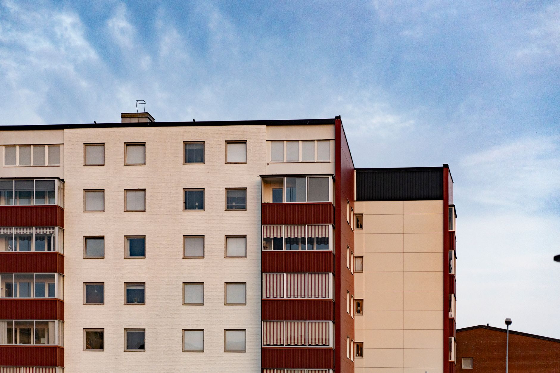 Contemporary apartment building facade with multiple windows and balconies against a clear sky.