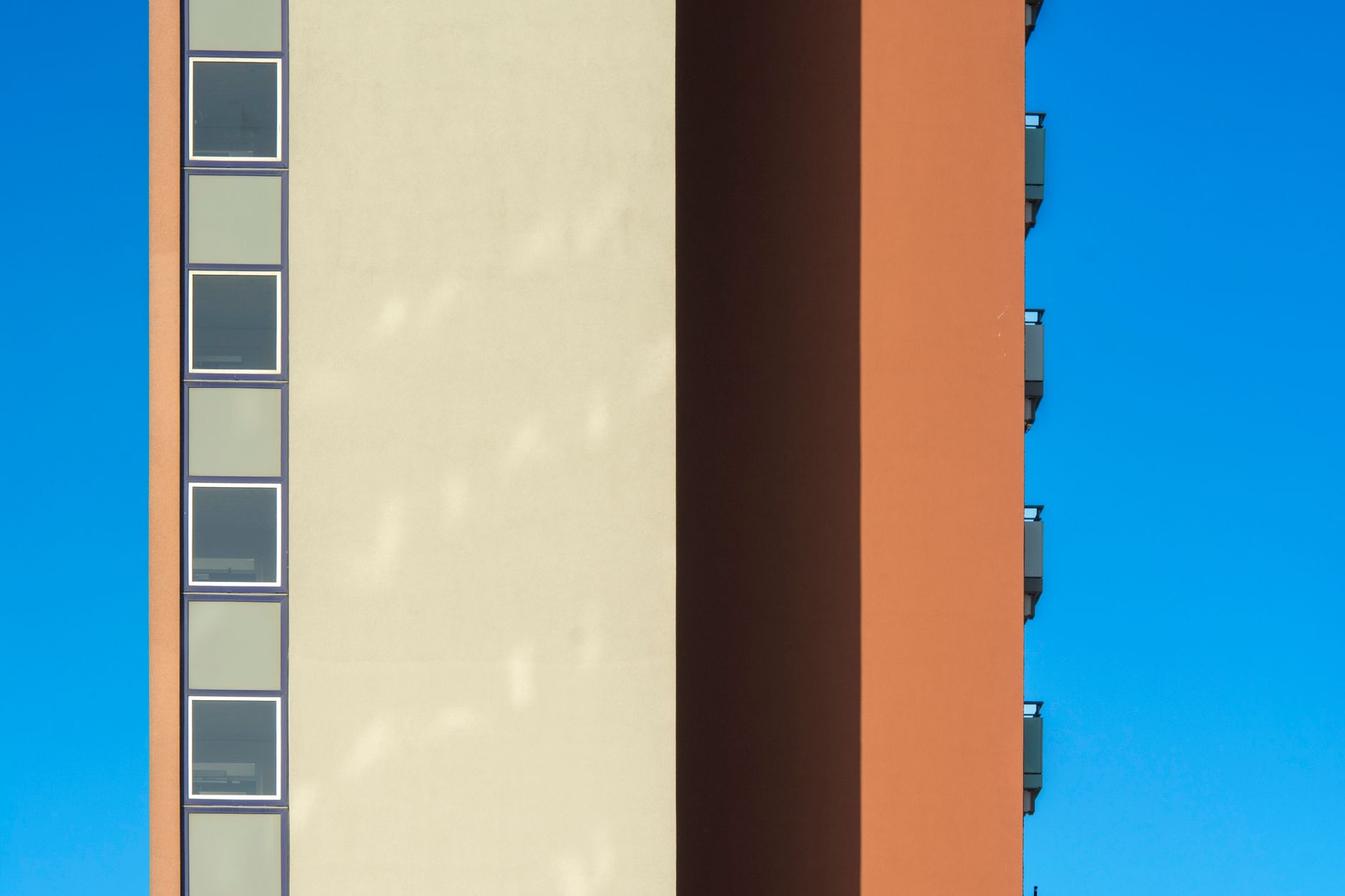 Minimalist view of a colorful high-rise residential building with striking architecture against a clear blue sky.