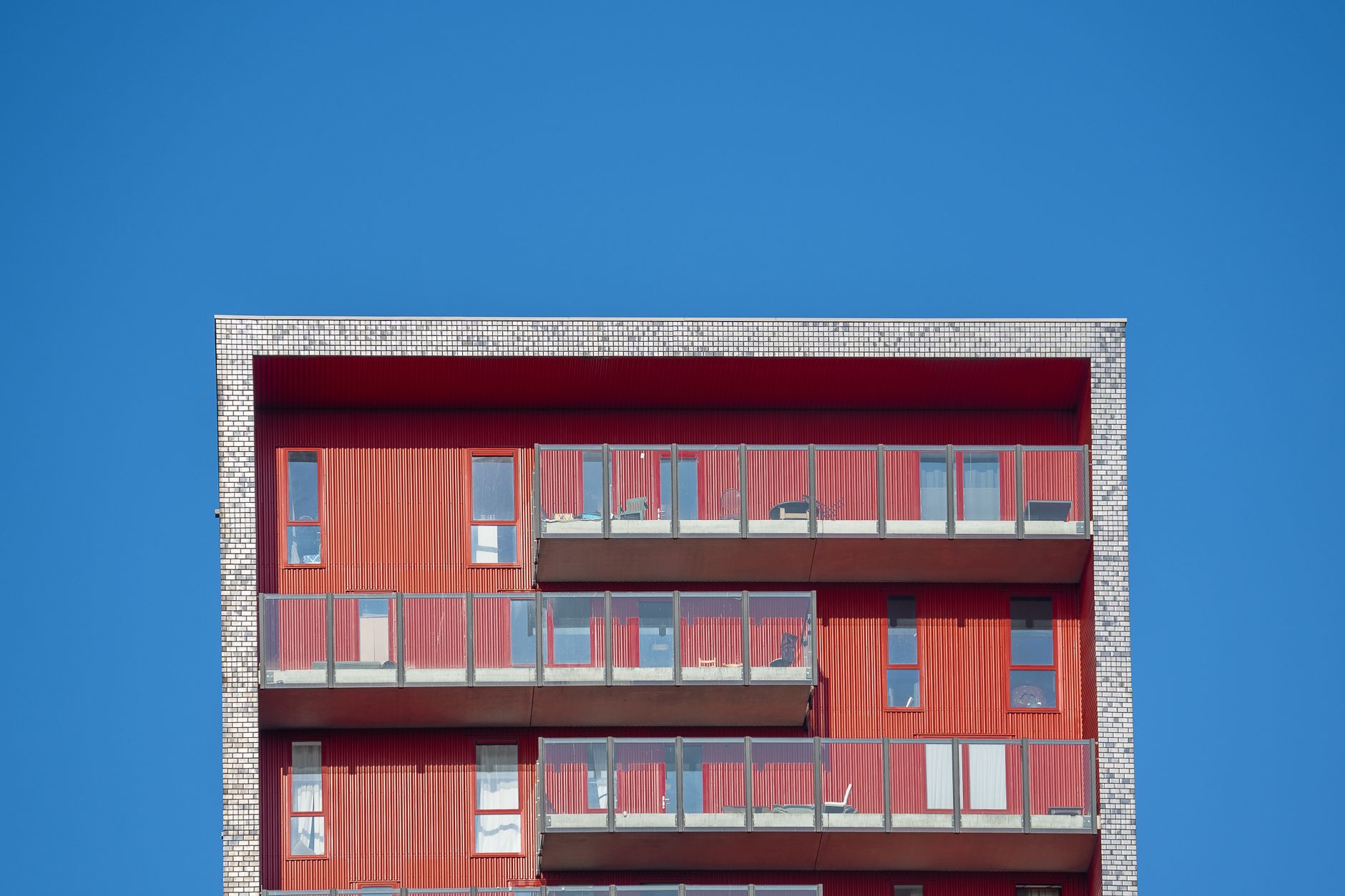 Minimalist design of a modern red building facade against a clear blue sky.