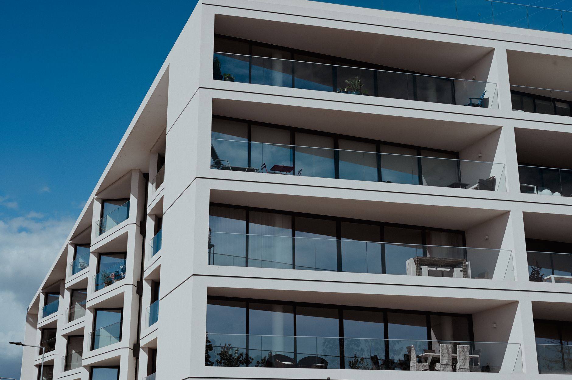 Contemporary apartment building in Faro, featuring sleek balconies and clear blue skies.