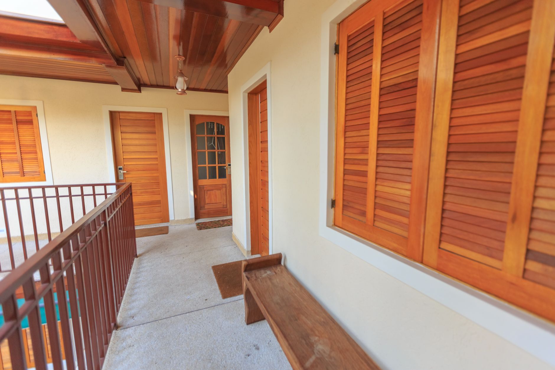 Indoor hallway with wooden shutters and doors, featuring an empty bench and modern ceiling design.