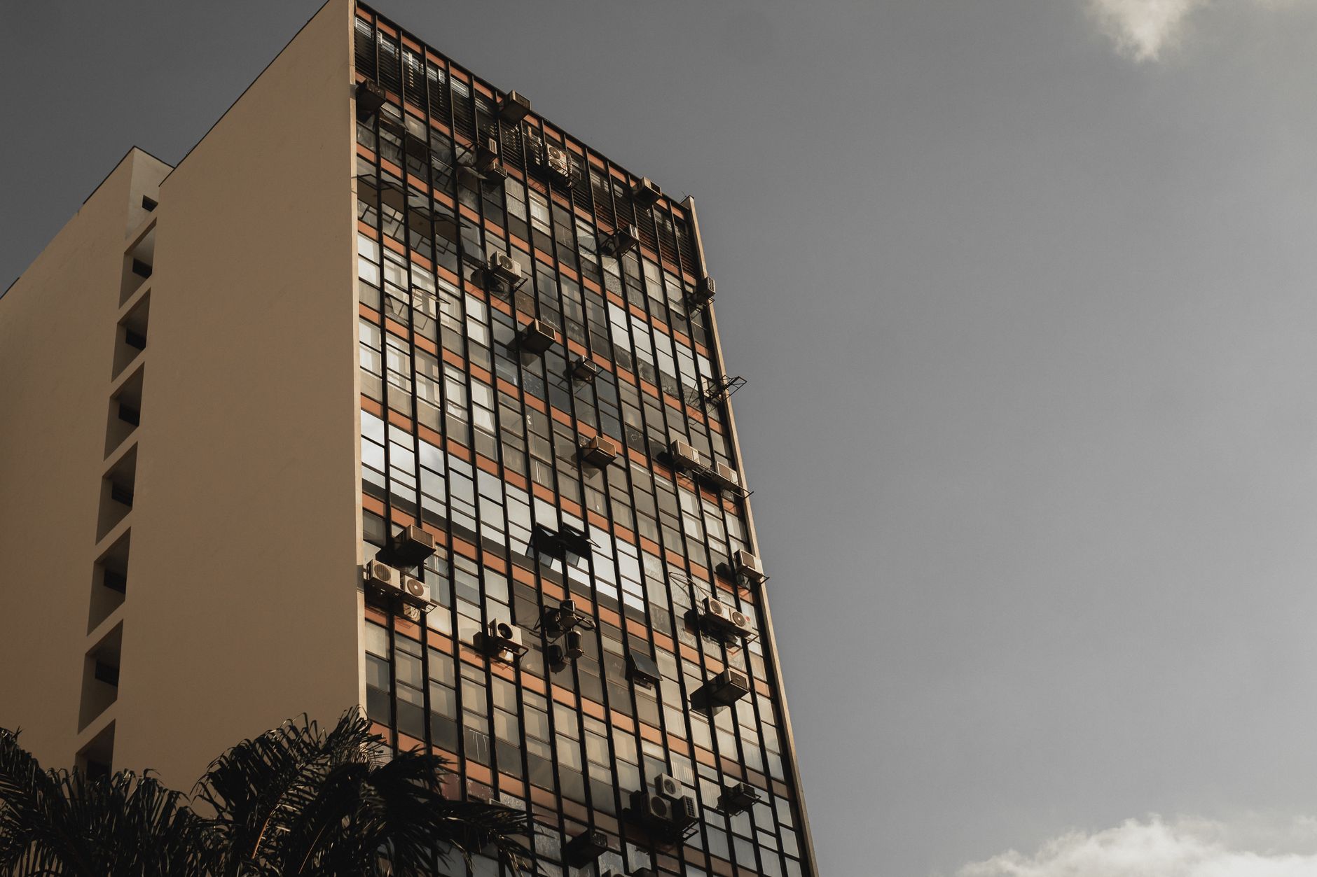 Low angle view of a high-rise building with a modern glass facade against a clear sky.