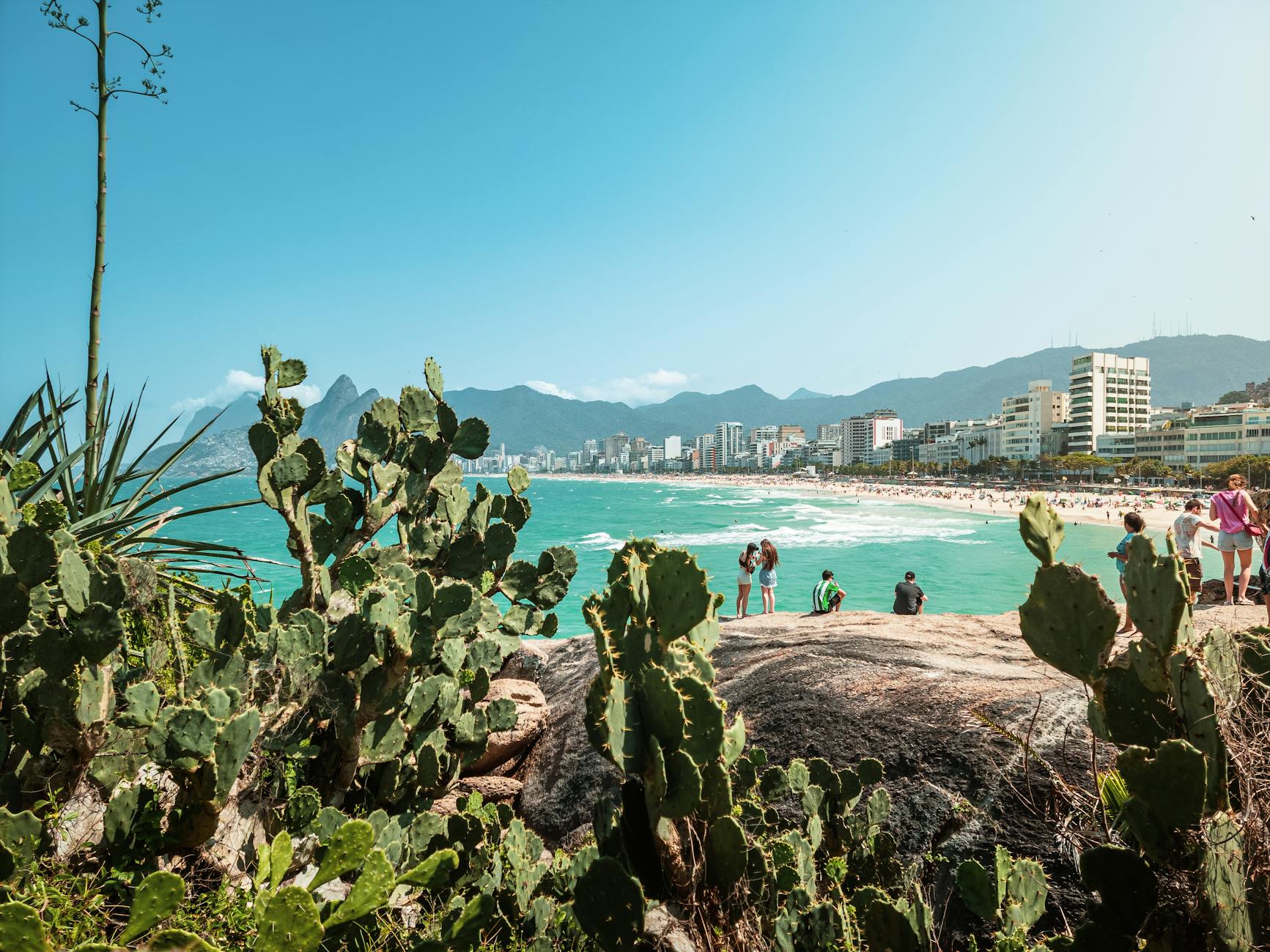 Vibrant view of Ipanema Beach with cacti and people enjoying a sunny day, Rio de Janeiro.