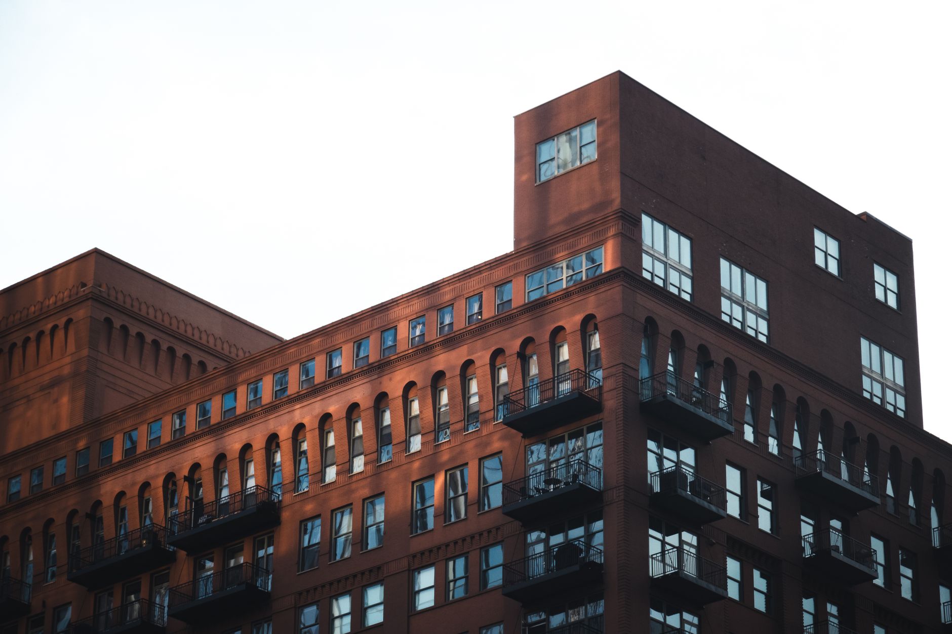 A modern industrial-style brick building with balconies and large windows.