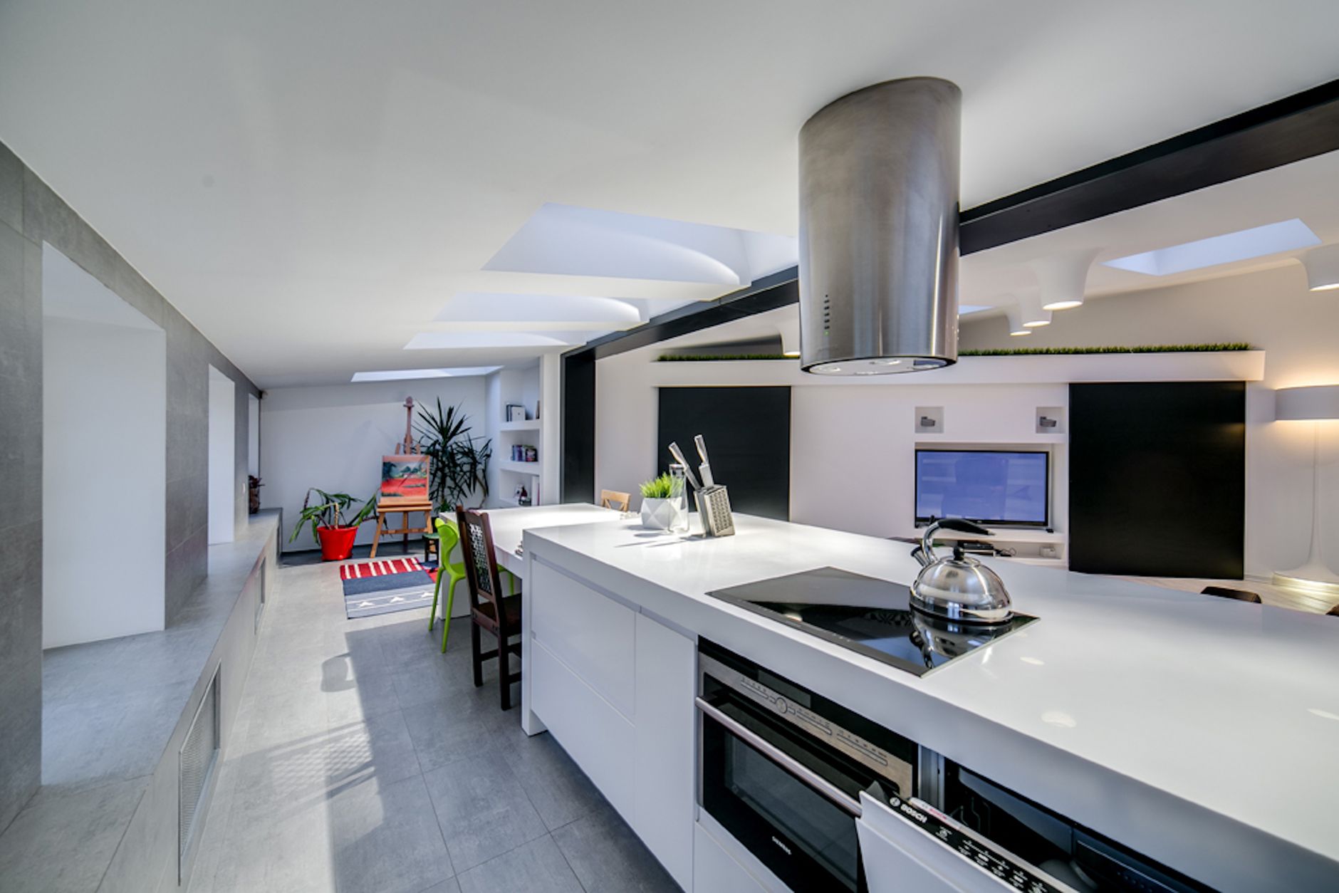 Bright and modern kitchen featuring open space design with sleek white surfaces and natural lighting.