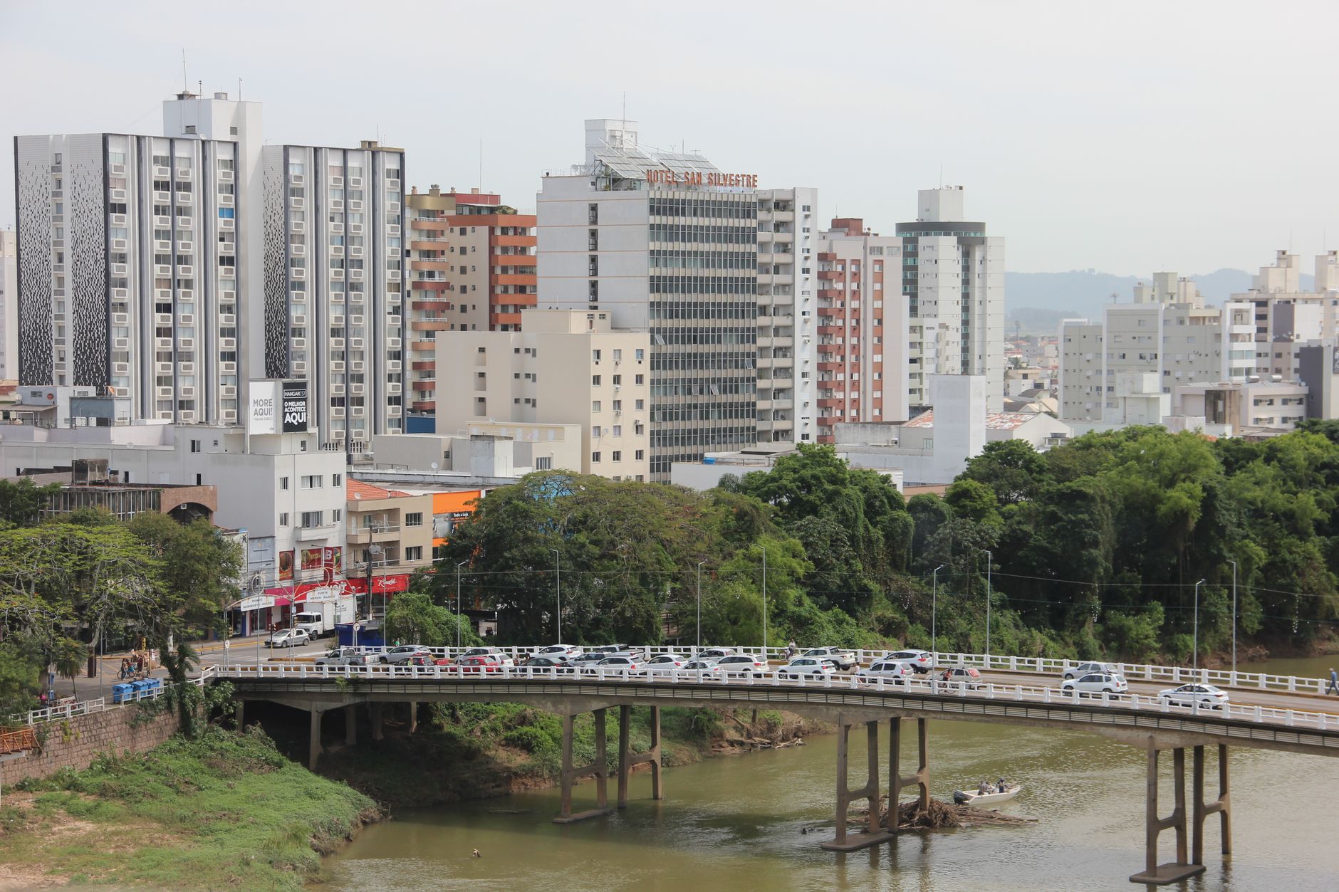 A bustling cityscape with buildings, bridge, and river during the day.